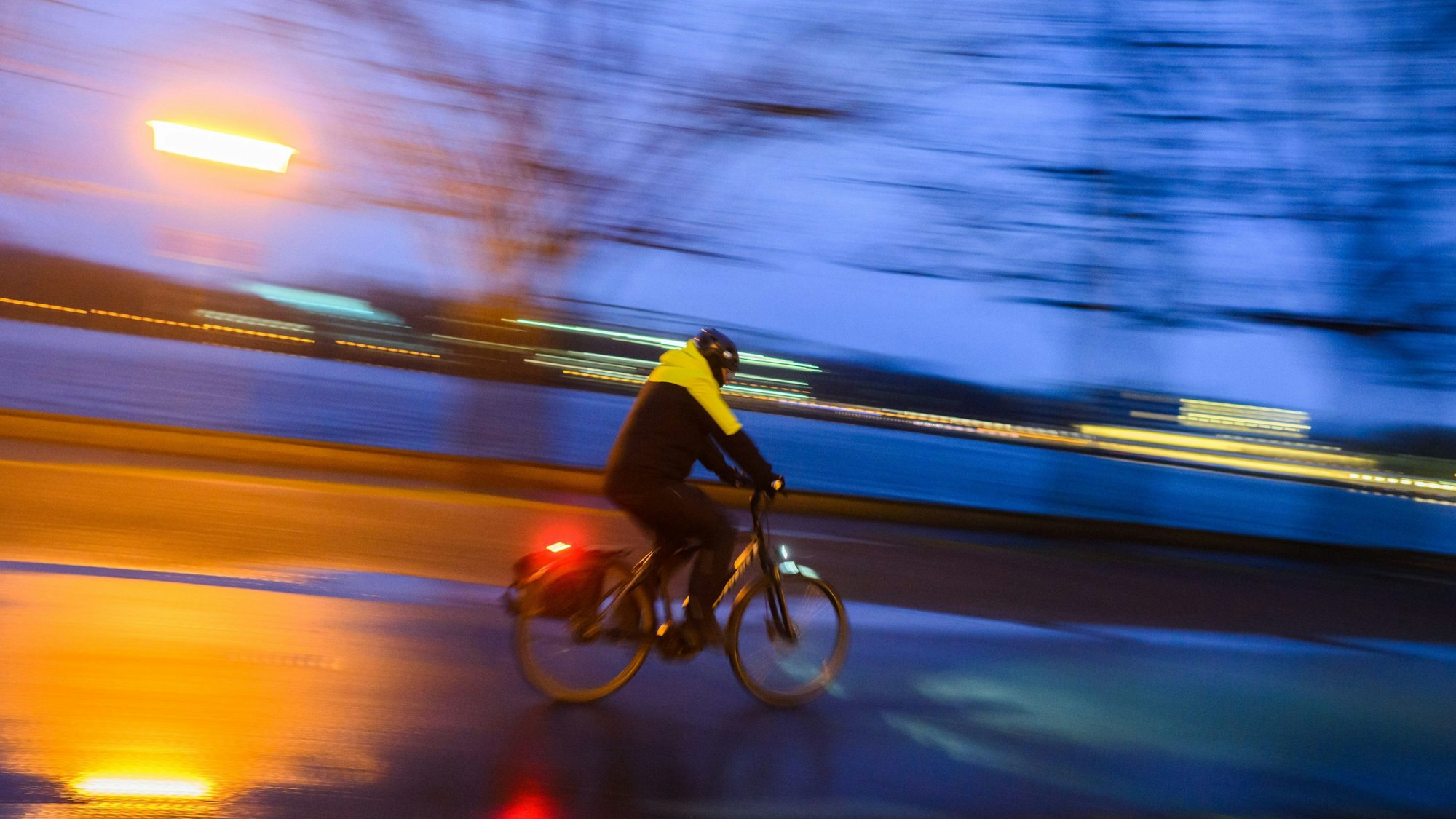 Ein Radfahrer fährt am frühen Morgen eine Straße entlang.