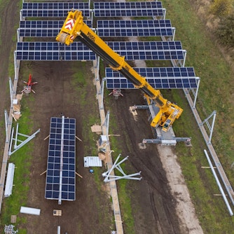 Mit einem Kran wird eine Agrar-Photovoltaik-Anlage montiert (die Aufnahme entstand mit einer Drohne). Im Wendland entsteht in einem Pilotprojekt die größte deutsche Agro-Photovoltaik-Anlage.