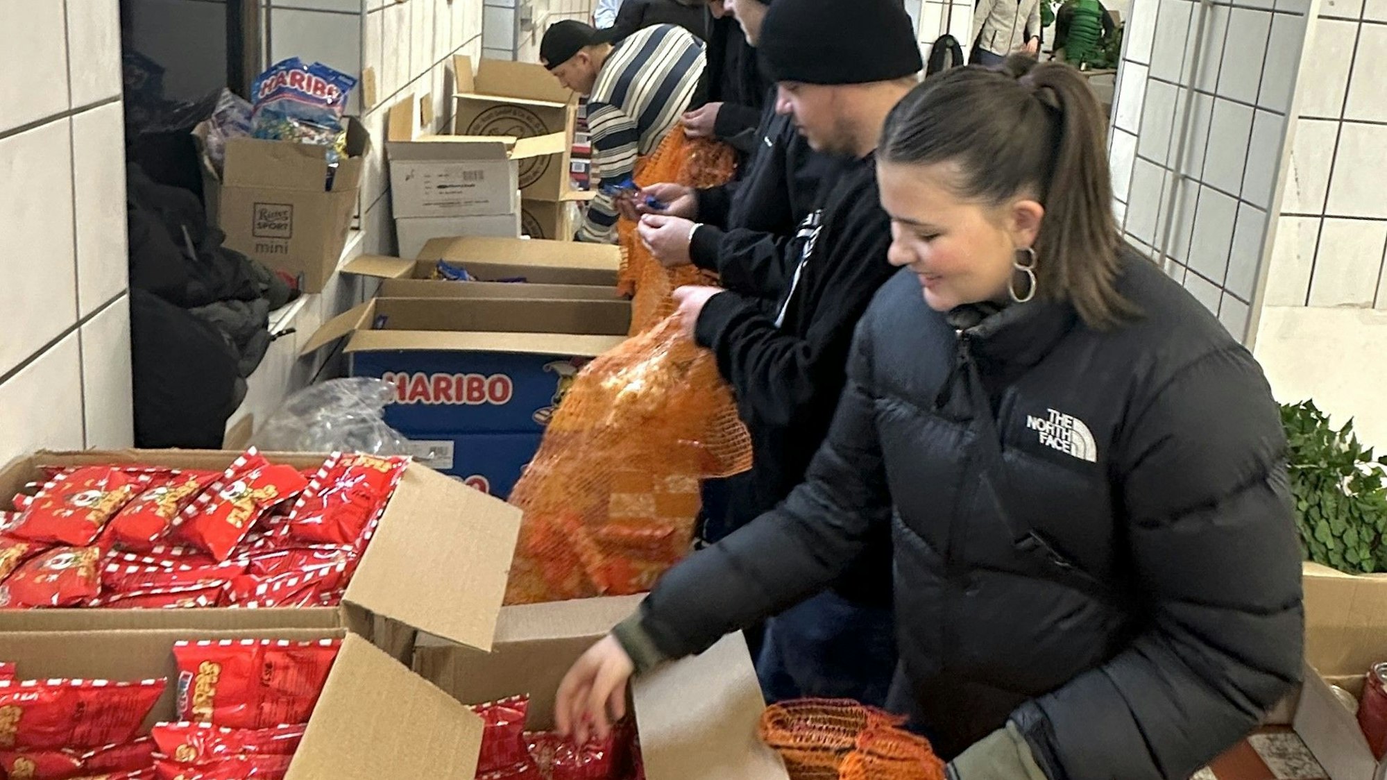 Männer und Frauen packen Süßigkeiten in Kartons.