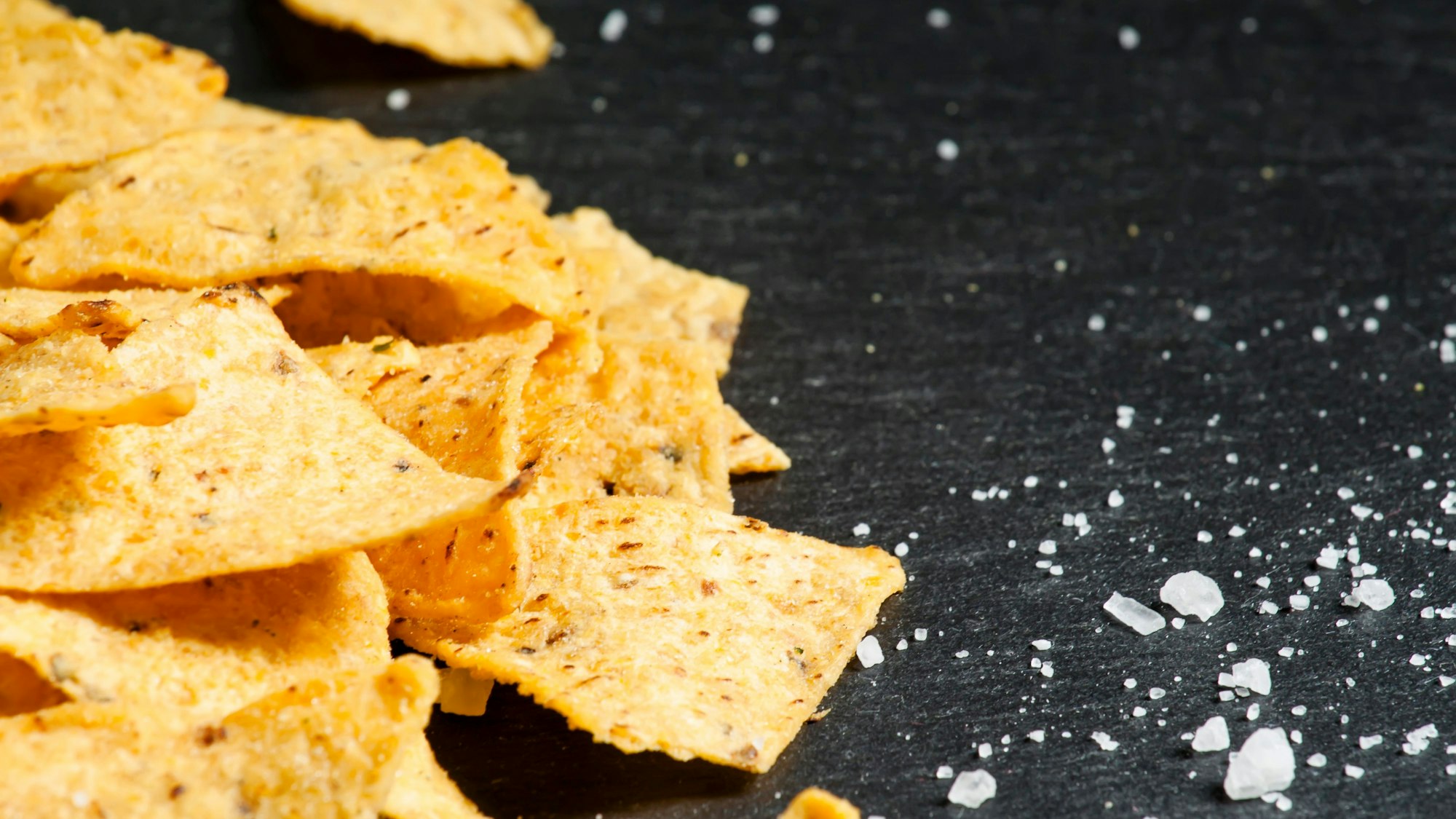 Tortillachips liegen auf schwarzem Untergrund