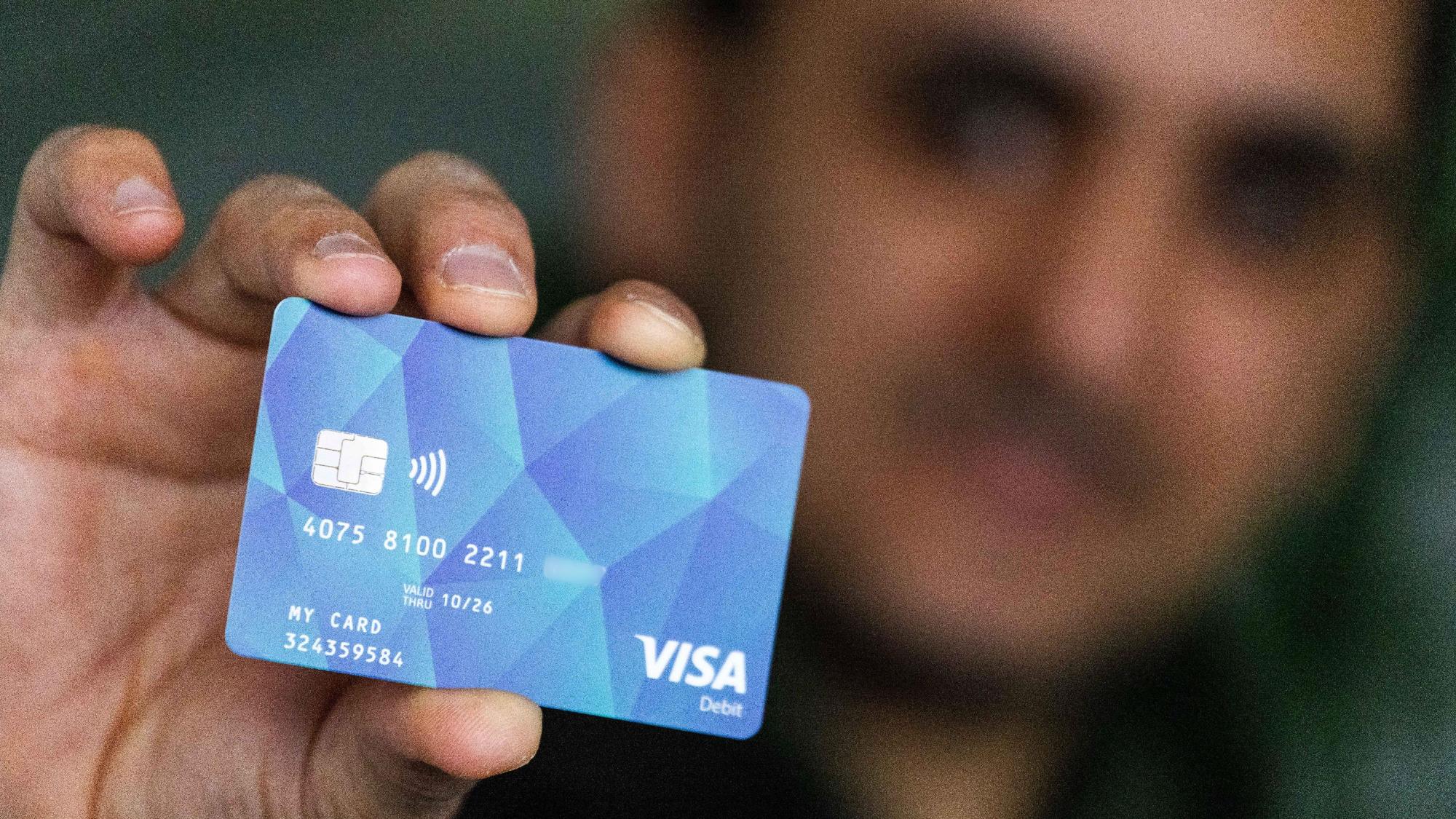 Das Symbolfoto zeigt einen Geflüchteten, der eine Bezahlkarte für Asylbewerber in der Hand hält.