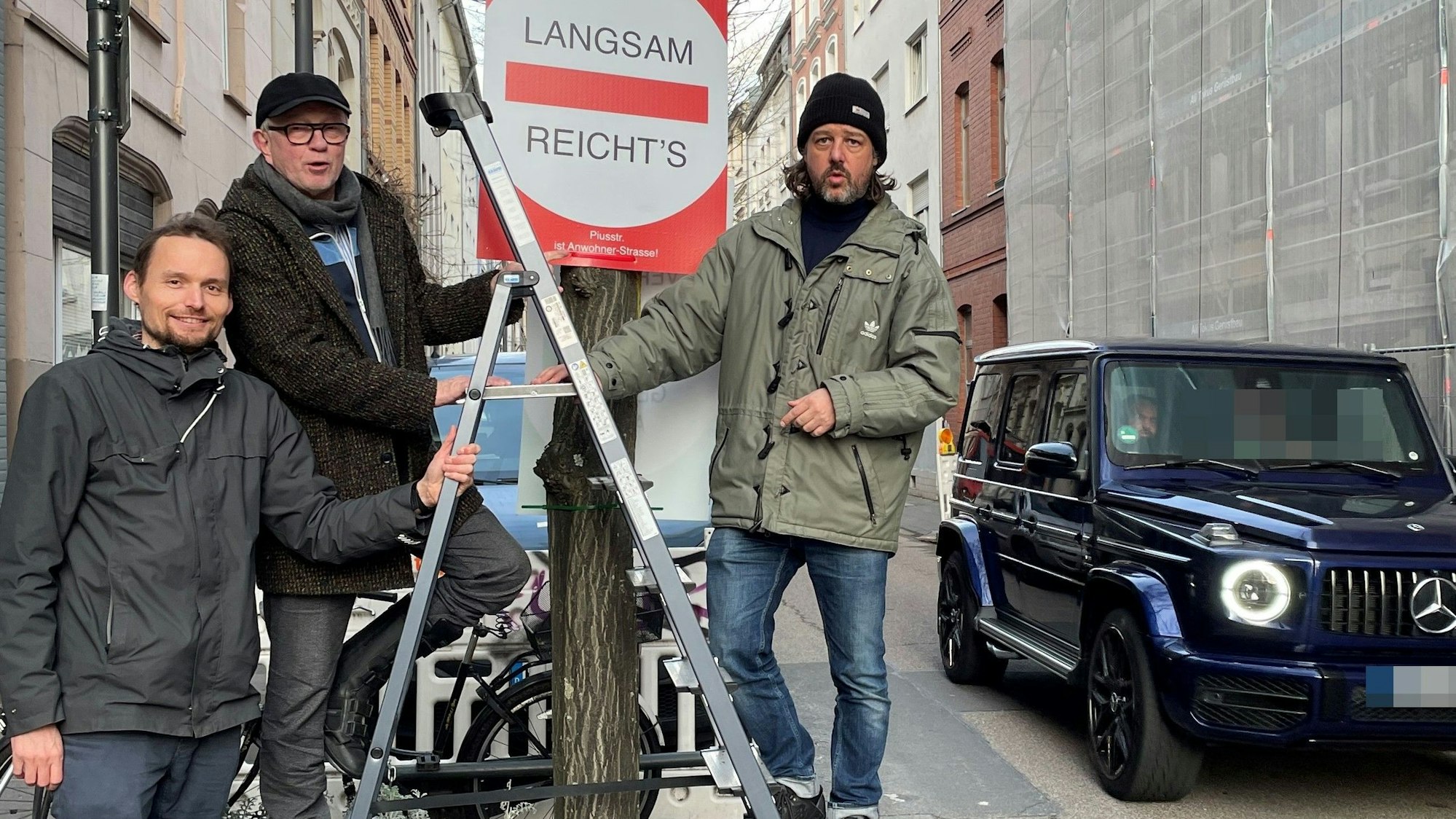 Drei Männer stehen um ein Baumbeet herum. Sie haben ein Schild aufgehängt.