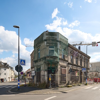 Blick auf ein Eckhaus, das von einem Bauzaun umstellt ist
