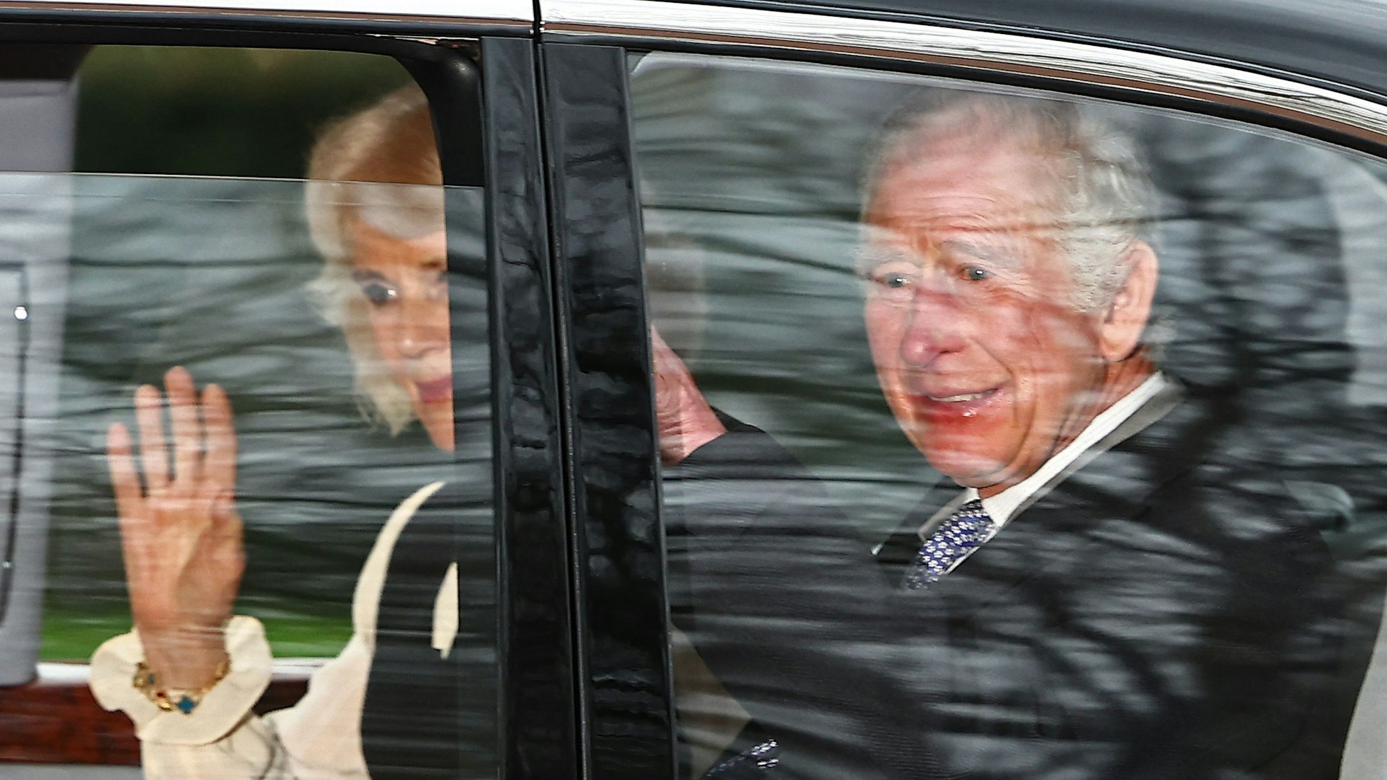 Britain's King Charles III and Britain's Queen Camilla wave as they leave by car from Clarence House in London on February 6, 2024. King Charles III's estranged son Prince Harry reportedly arrived in London on Tuesday after his father's diagnosis of cancer, which doctors "caught early". (Photo by HENRY NICHOLLS / AFP)
