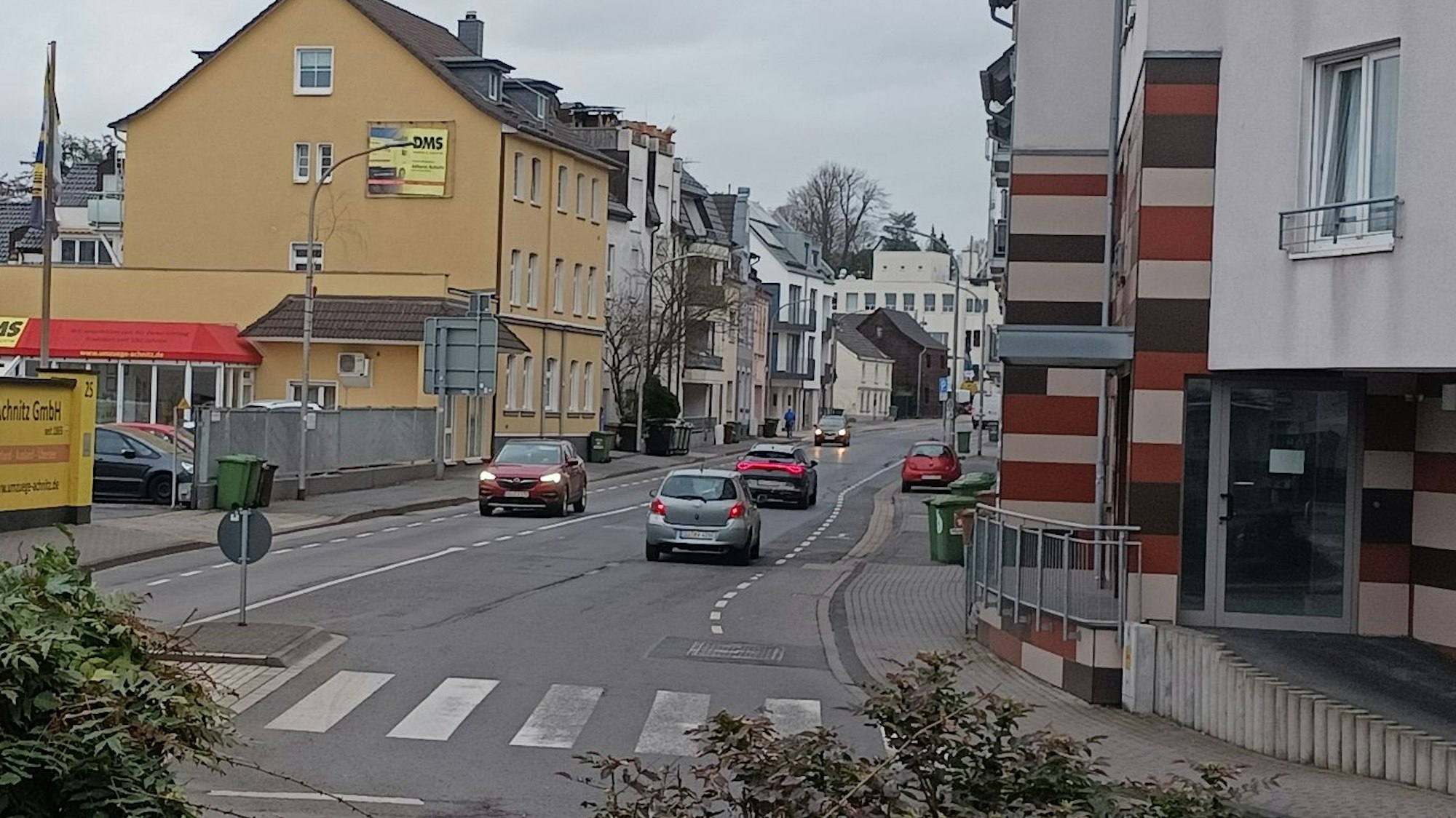 Autos befahren eine breite Straße, im Vordergrund ein Zebrastreifen
