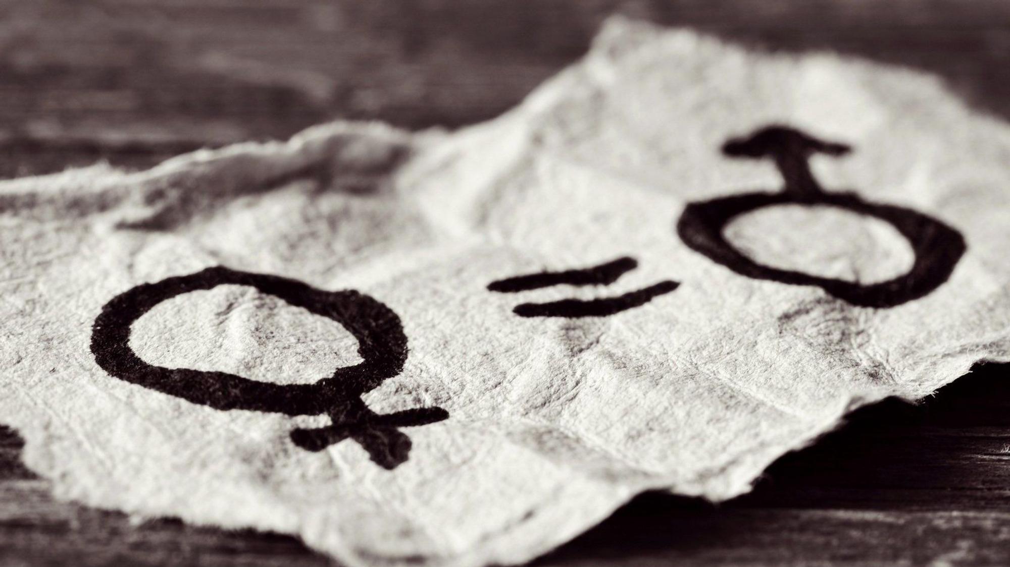 Frauensymbol und Männersymbol auf einem Zettel, dazwischen ein Gleichzeichen
