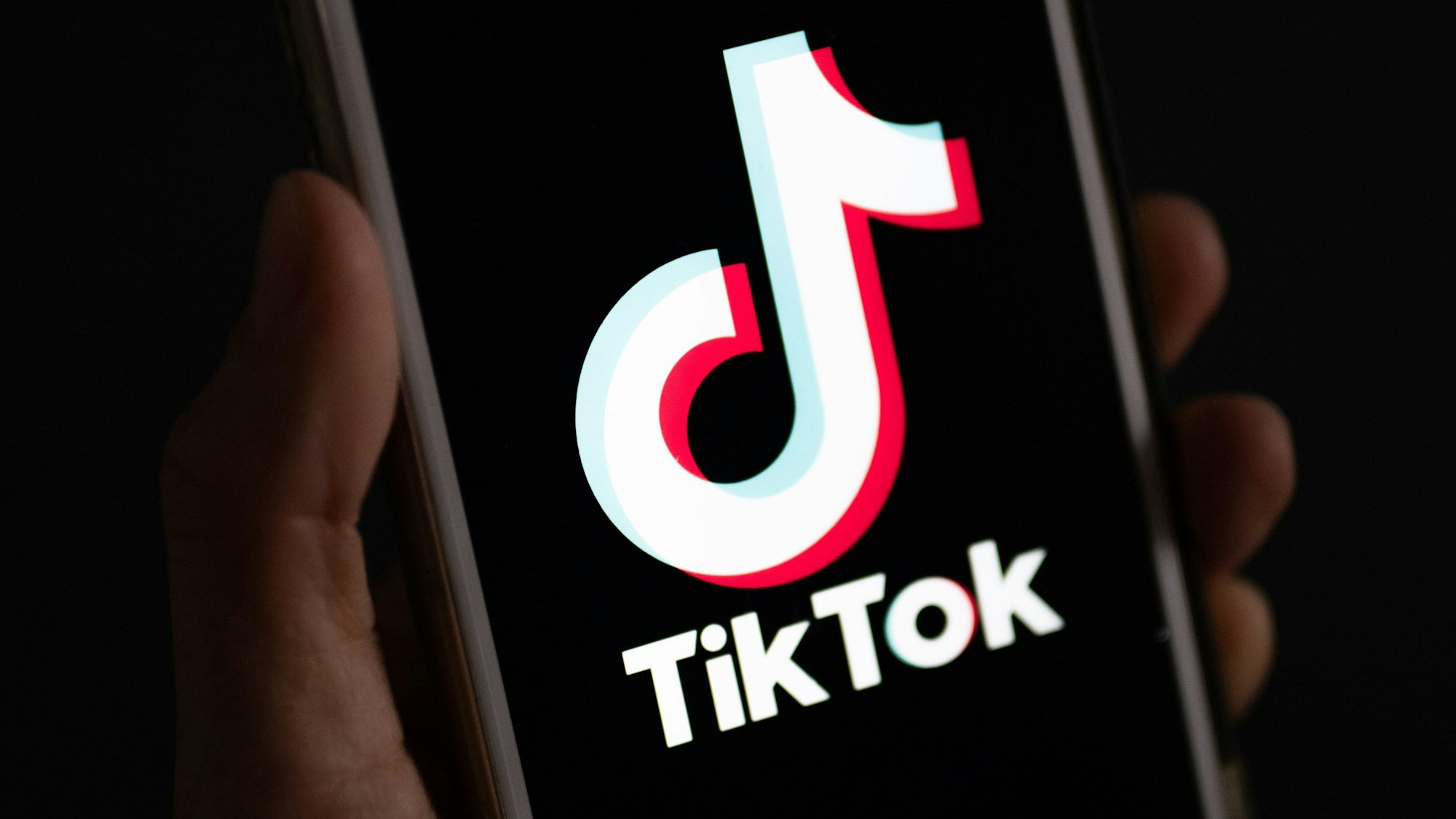Eine Hand hält ein Smartphone in der Hand, auf dem die TikTok-App installiert ist.