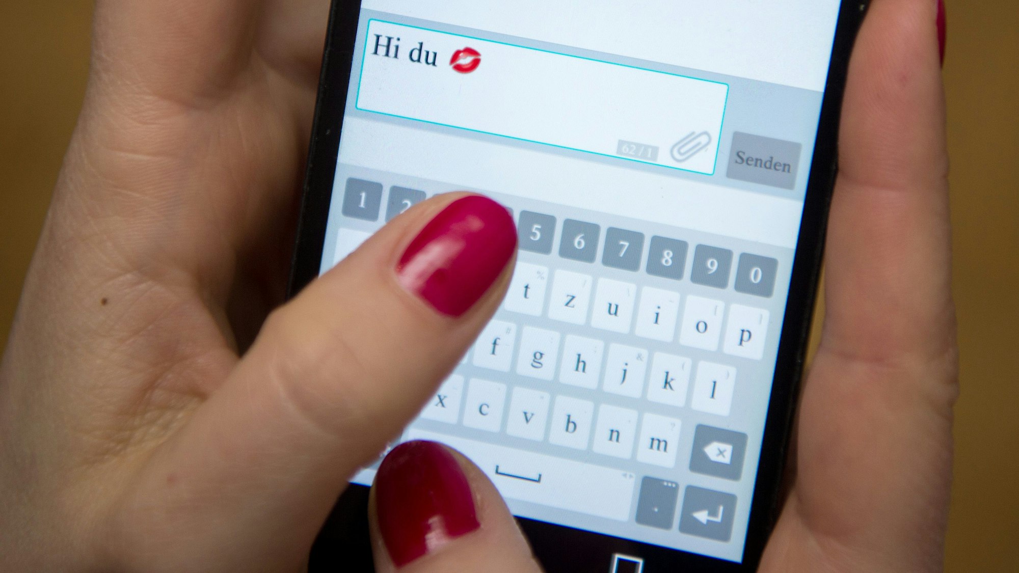 Eine junge Frau tippt auf einem Smartphone eine Nachricht mit dem Text „Hi du“.