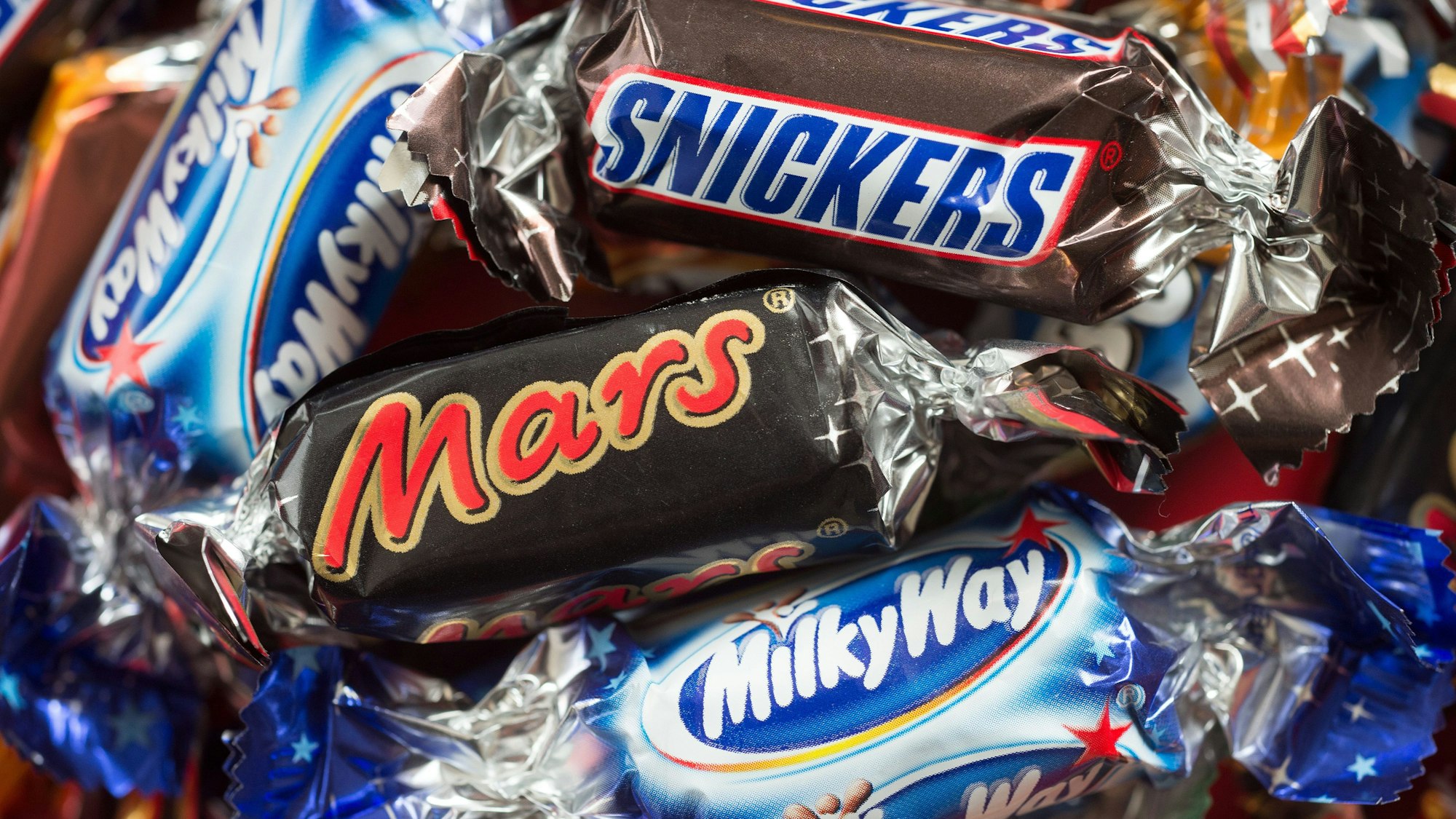 Schokoriegel des US-Lebensmittelkonzerns Mars liegen ausgebreitet auf einem Tisch. Der Streit mit der Edeka-Gruppe ist beigelegt. (Symbolfoto)