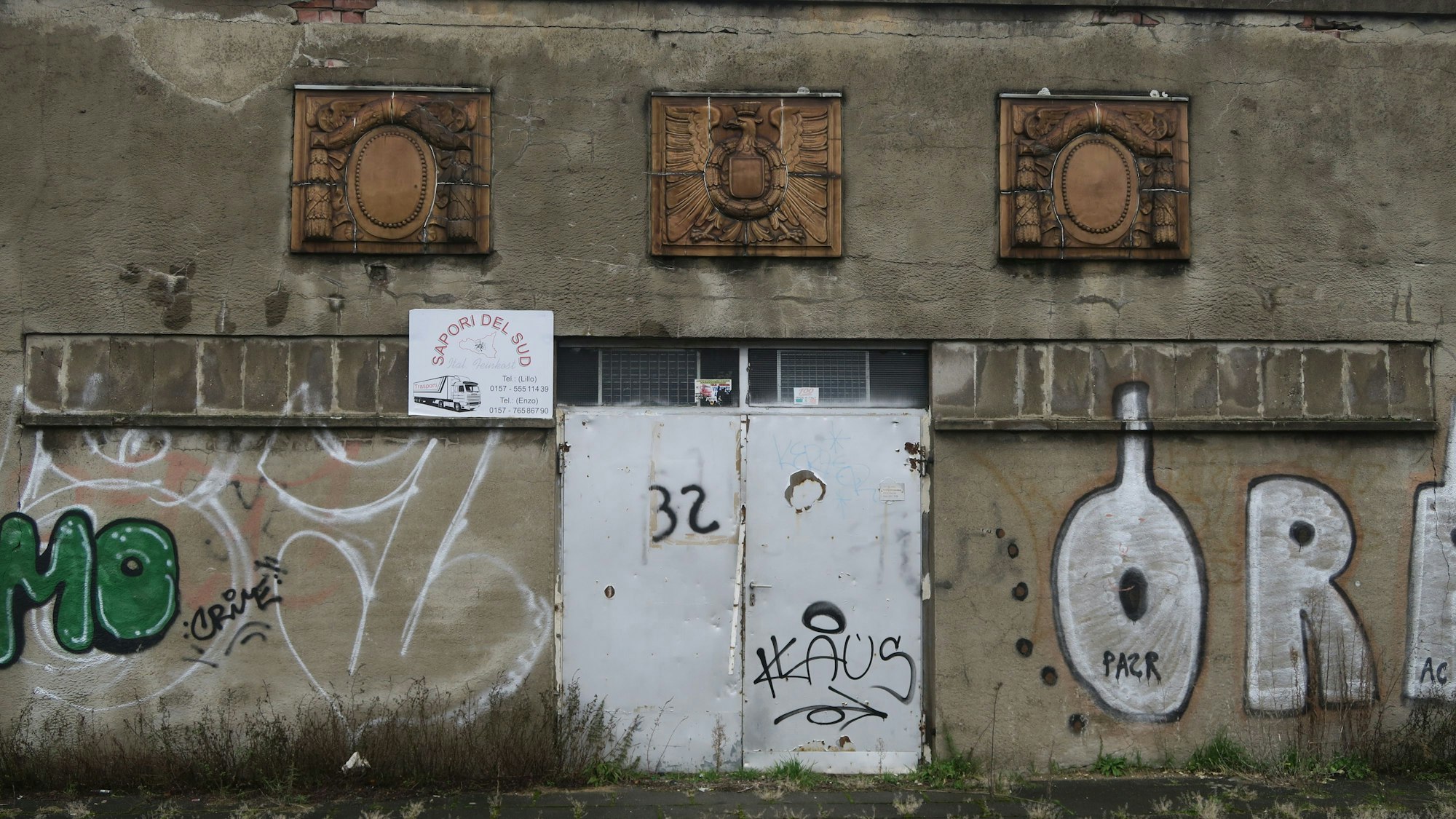 Blick auf Ornamente an einer mit Graffiti beschmierten Betonwand.