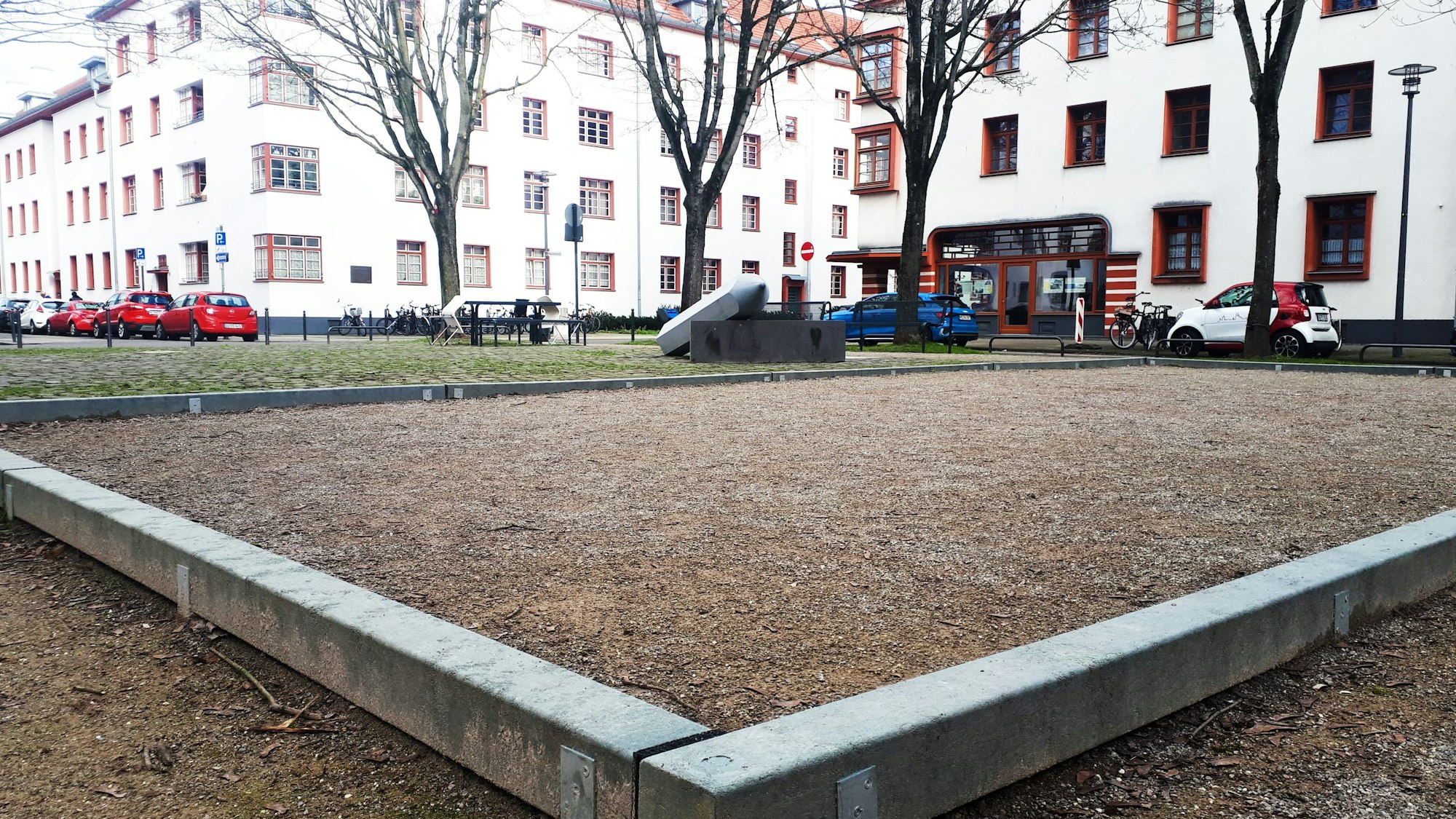 Blick auf einen Platz mit Bouleplatz vor einer Wohnsiedlung