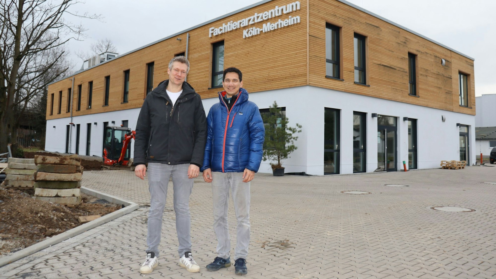 Zwei Männer stehen vor einem neuen zweistöckigen Gebäude mit der Aufschrift Fachtierarztzentrum Köln-Merheim.