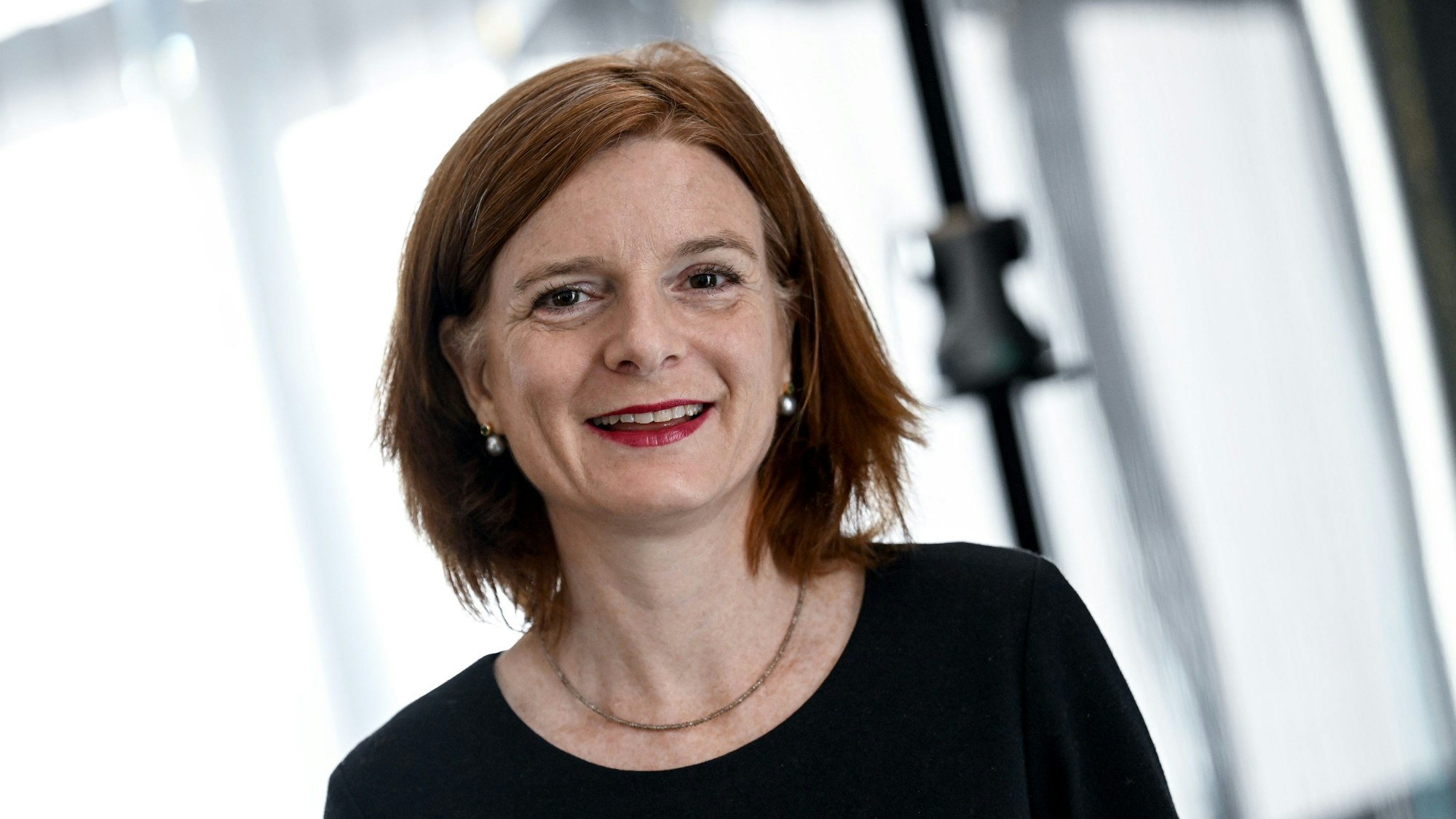 Katrin Vernau lächelt in die Kamera. Sie trägt ein schwarzes Oberteil und eine goldene Kette.