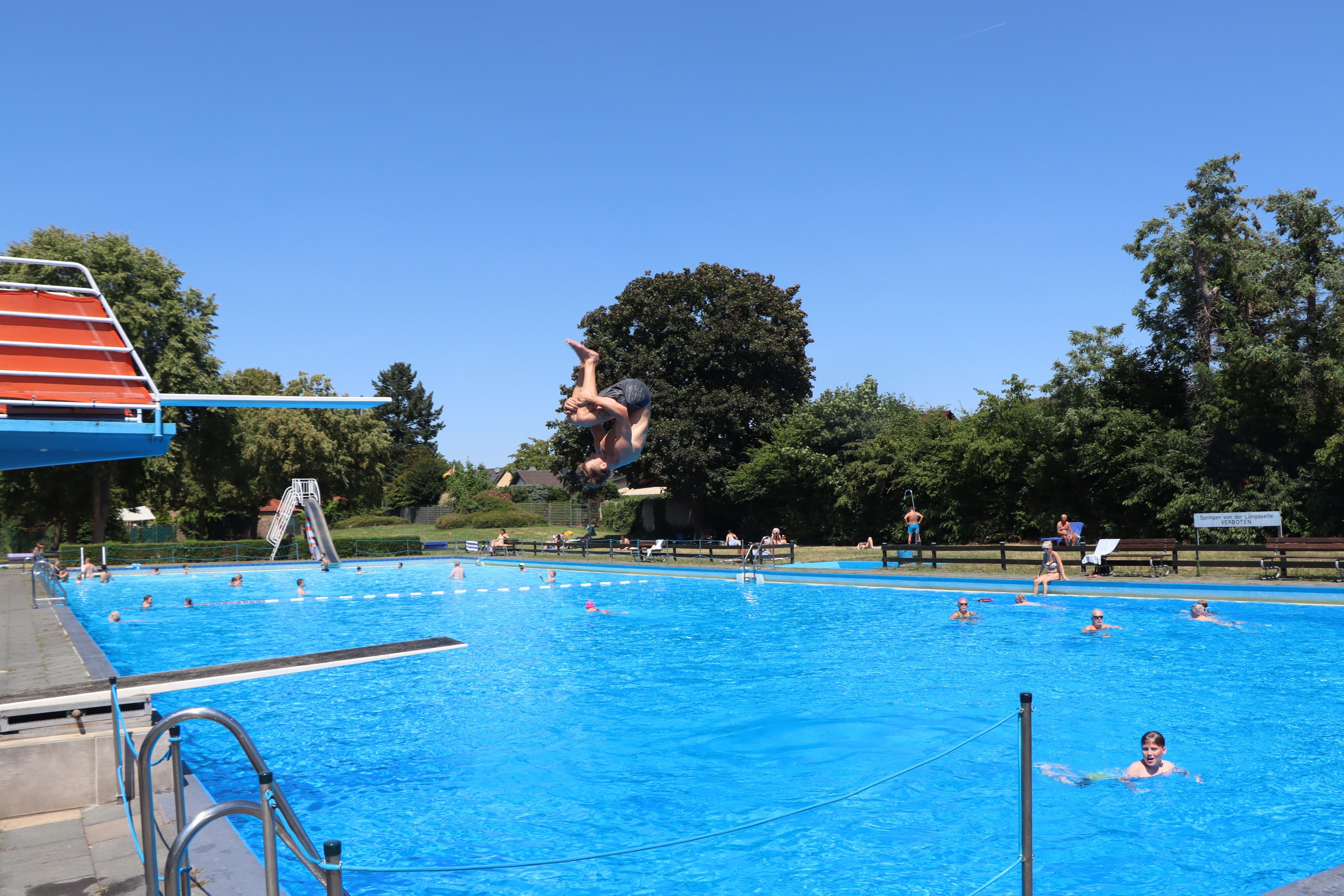Zu sehen ist ein Freibad, in dem sich Schwimmerinnen und Schwimmer aufhalten.