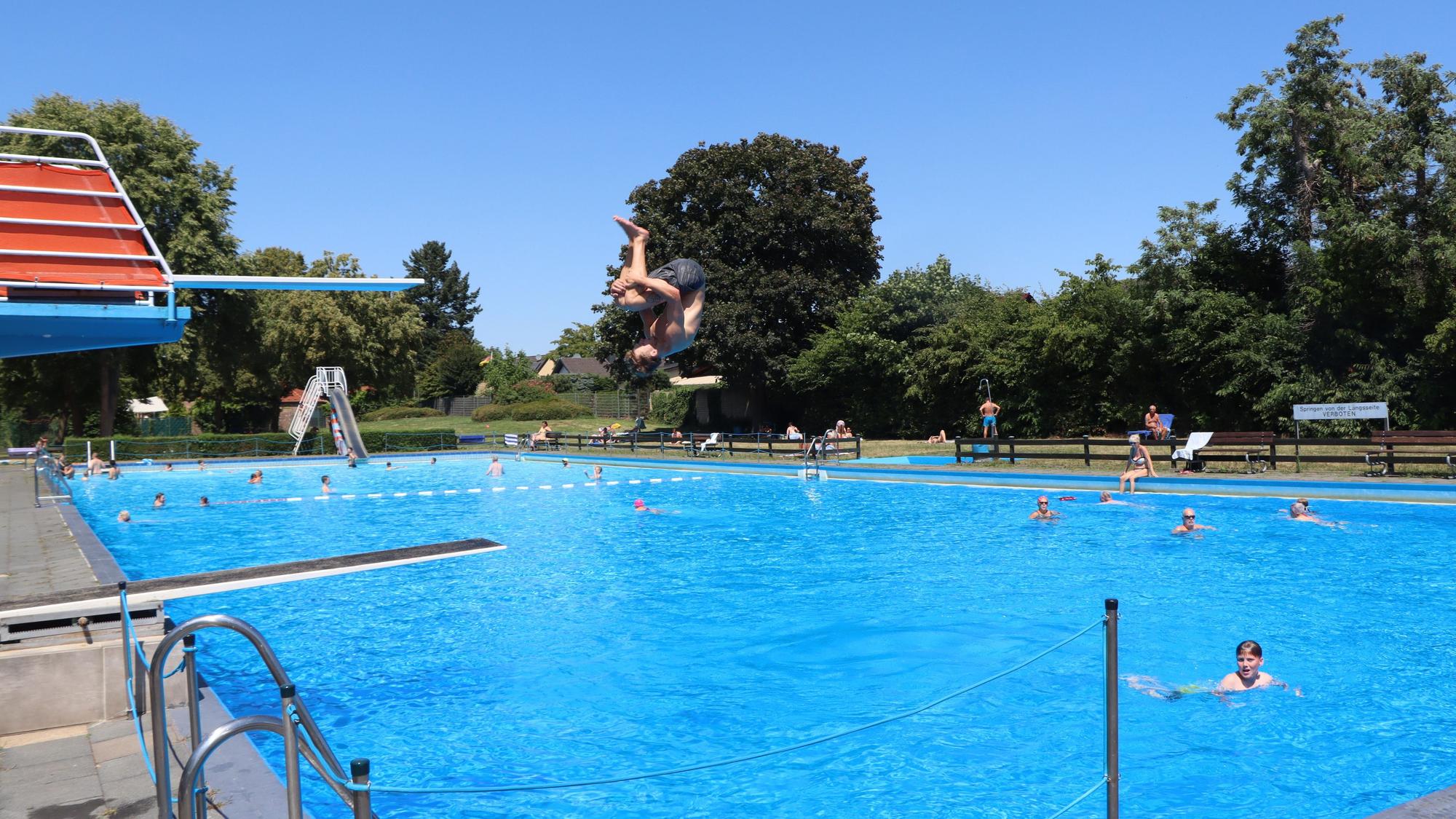 Zu sehen ist ein Freibad, in dem sich Schwimmerinnen und Schwimmer aufhalten.