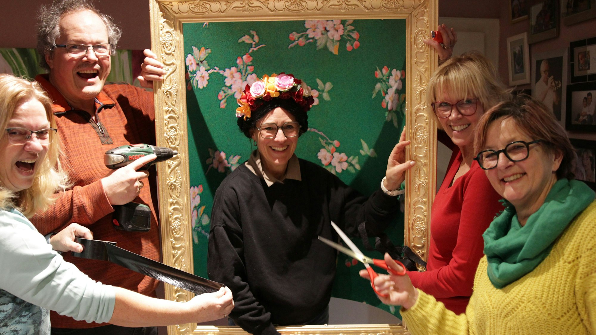 Die Vussemer Jecke bereiten ihre Kostüme vor: Eine Frau steht in einem Bilderrahmen, andere haben Bohrmaschine und Schere in der Hand.