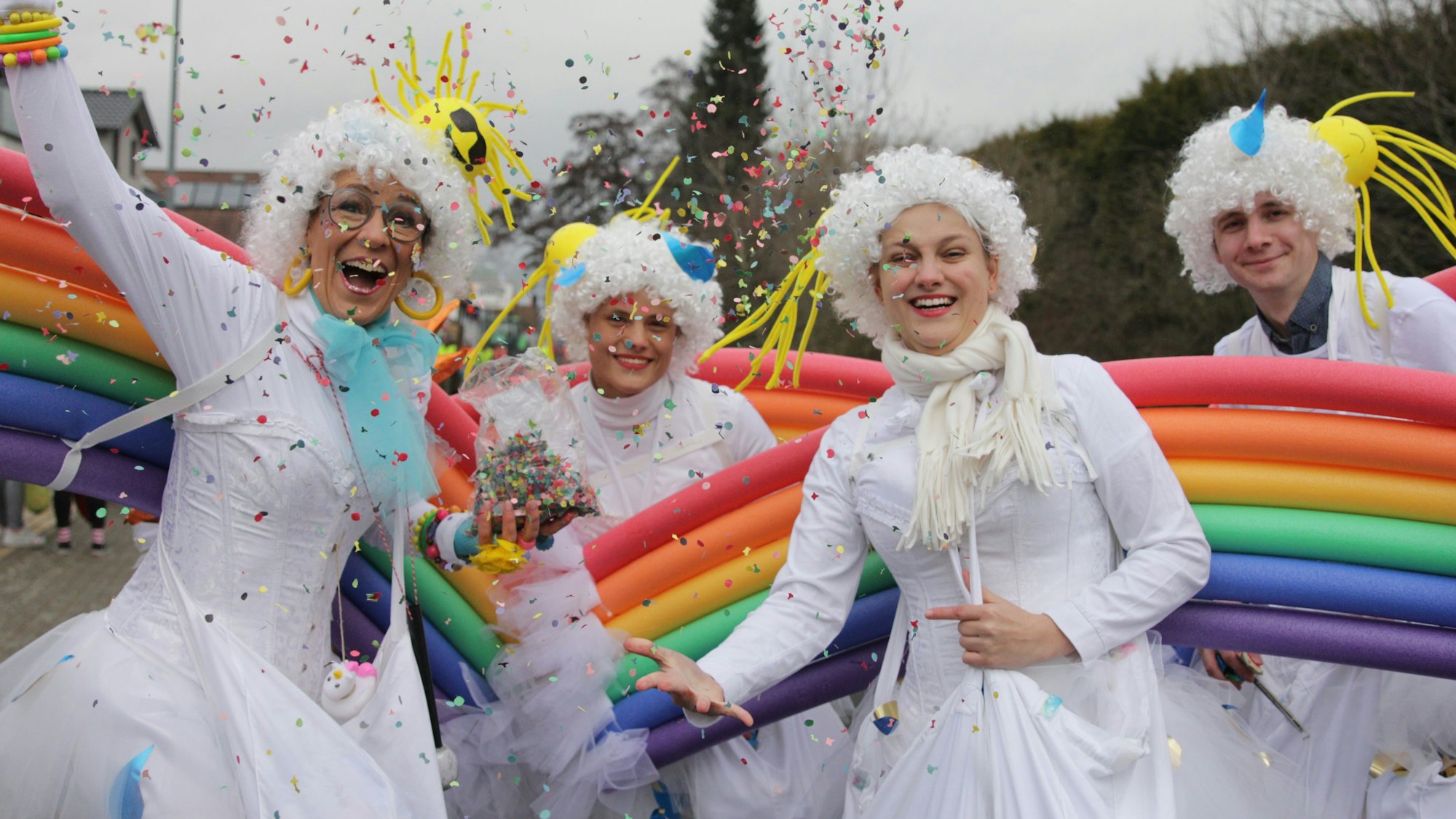 Das Bild zeigt als Regenbogen verkleidete Jecke beim Zoch in Vussem.