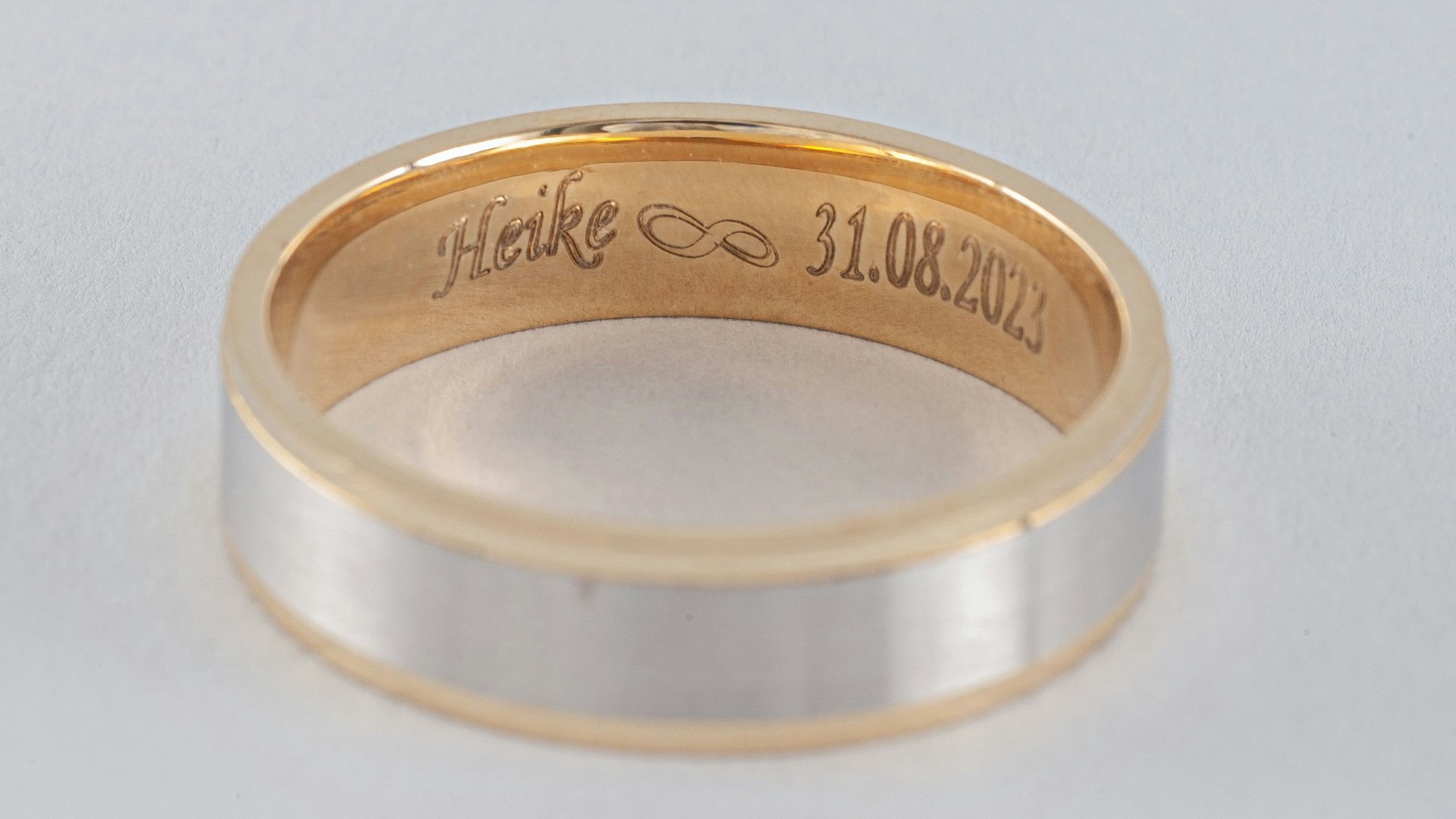 Zu sehen ist ein Goldring mit Gravur.