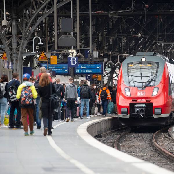 Bahnreisende warten auf dem Bahnsteig auf die Einfahrt des Zuges im Kölner Hauptbahnhof.