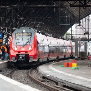 Bahnreisende warten auf dem Bahnsteig auf die Einfahrt des Zuges im Kölner Hauptbahnhof.