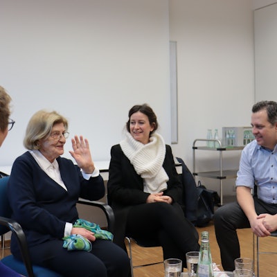 Eva Szepesi und einige ihrer Zuhörerinnen und Zuhörer sitzen auf Stühlen nebeneinander.