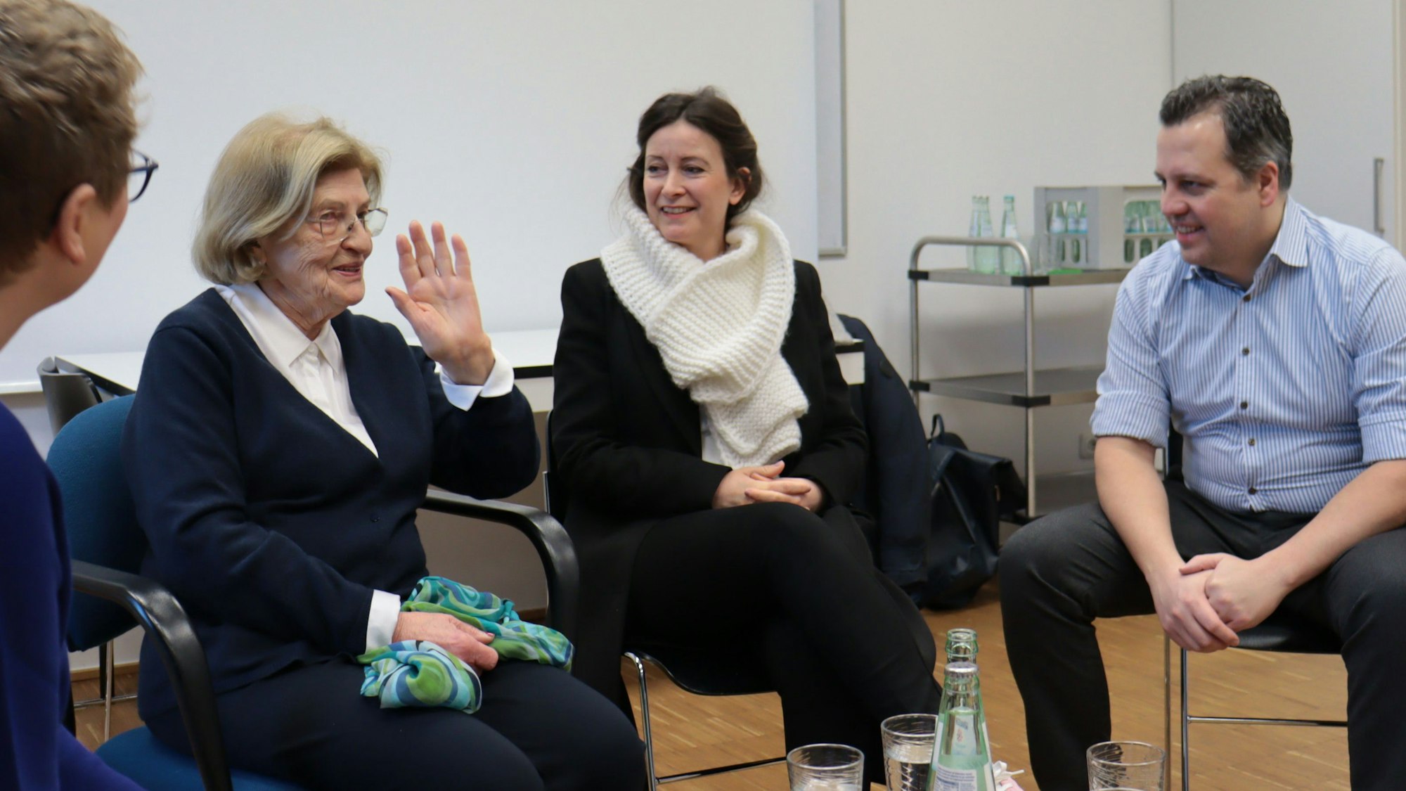 Eva Szepesi und einige ihrer Zuhörerinnen und Zuhörer sitzen auf Stühlen nebeneinander.