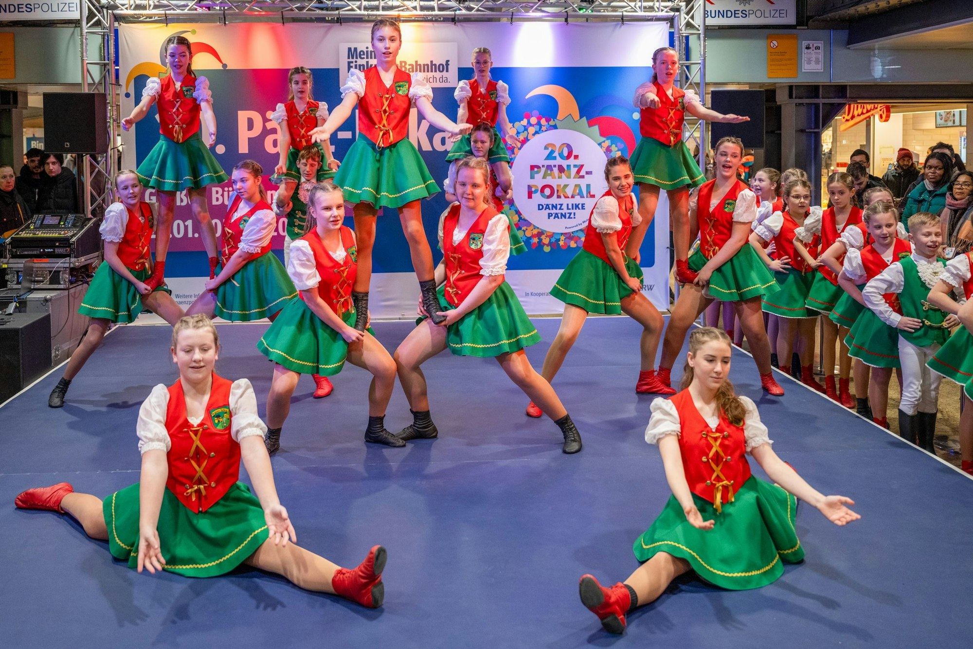 Kinder tanzen in rot-grünen Kostümen auf der Bühne.