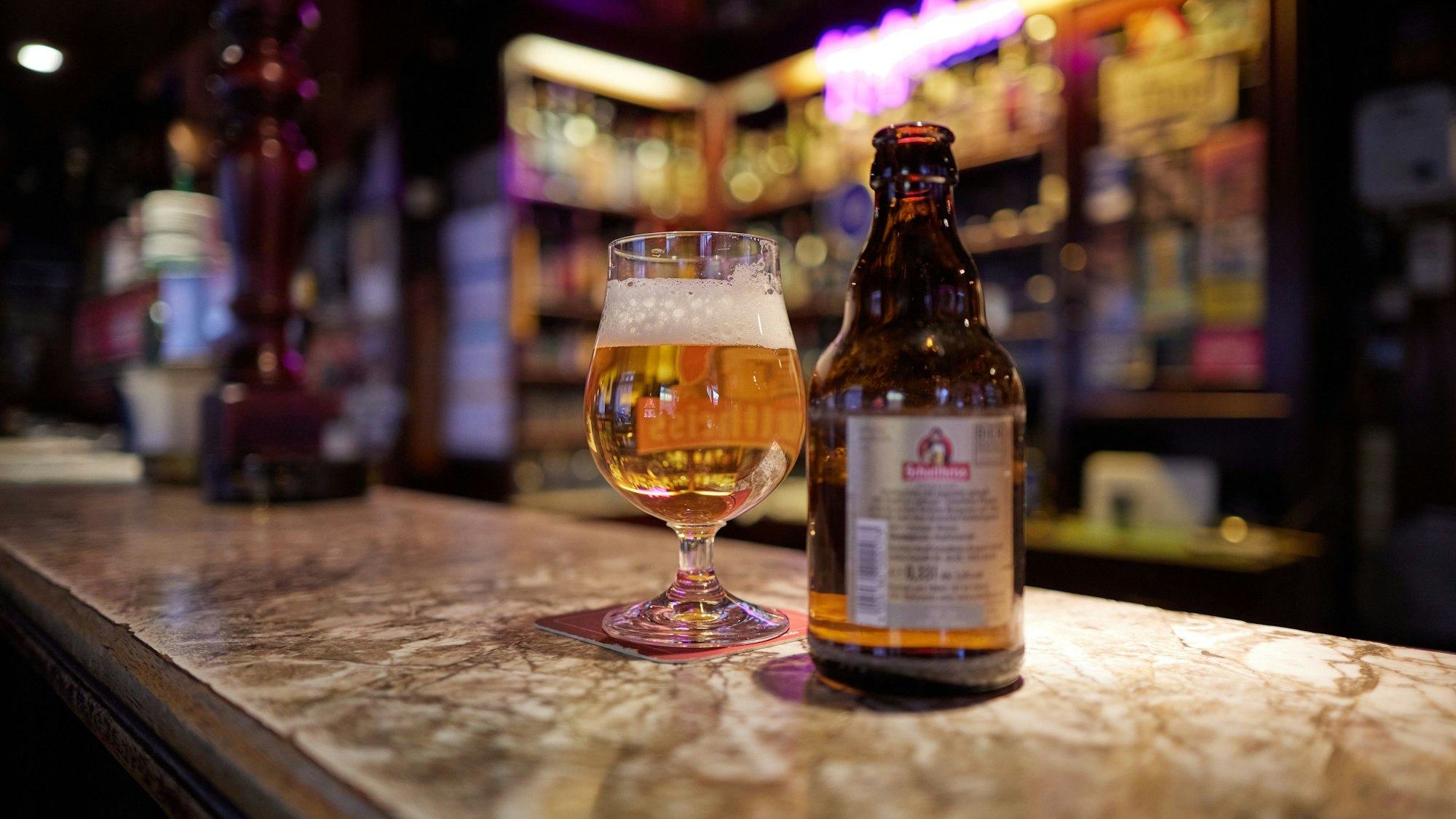 Eine Flasche Bier und ein Glas mit Bier stehen auf dem Tresen von der Kult-Kneipe „Kupferkanne “in der Steinmetzstraße in Schöneberg.