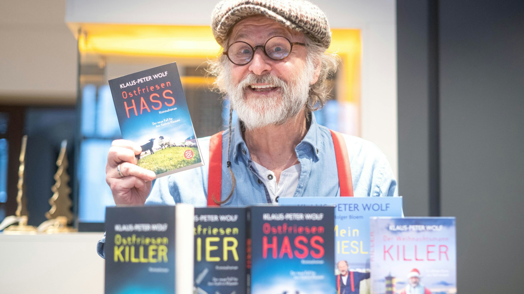 Klaus-Peter Wolf sitzt mit seinen Büchern im Café ten Cate, vor ihm stehen seine Ostfriesenkrimis.