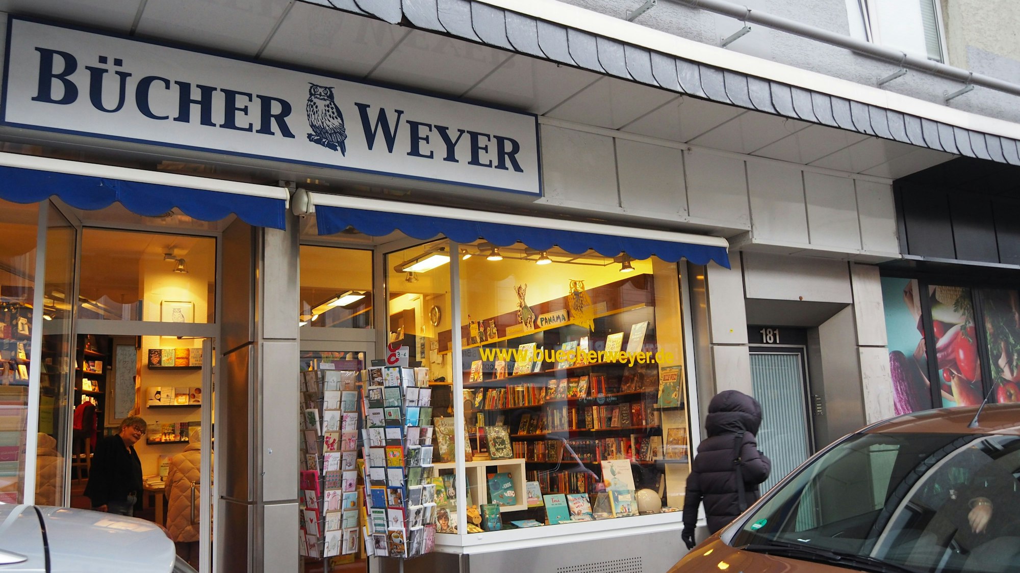 Der Bücherladen Bücher Weyer ist zu sehen. Autos parken davor.