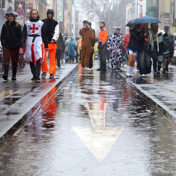 Kostümierte gehen über die nasse Zülpicher Straße.