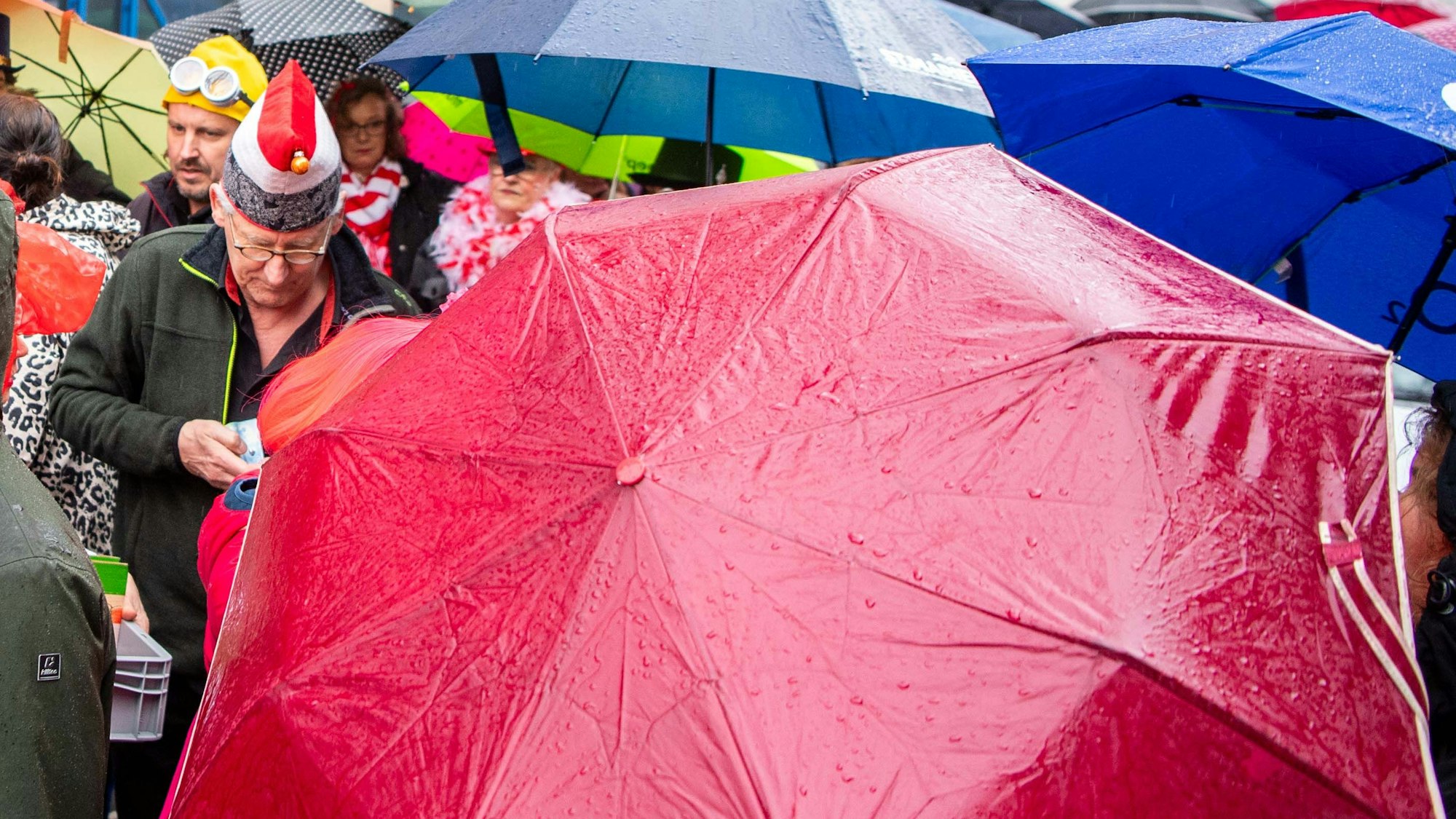 Casino-Chef Hermann Verbeek verkauft Getränke-Marken in der Warteschlange - und kämpft gegen zahlreiche Regenschirme.