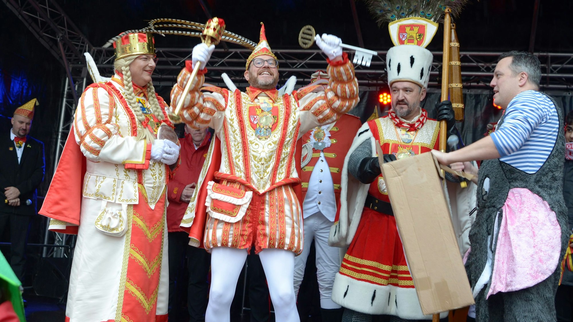 Da ist das Ding! Prinz Tobi I., flankiert von Jungfrau Martina und Bauer Sascha, präsentiert den Stadtschlüssel, den er in die Höhe reckt. Am Bildrand steht der geschlagene Bürgermeister Sacha Reichelt.