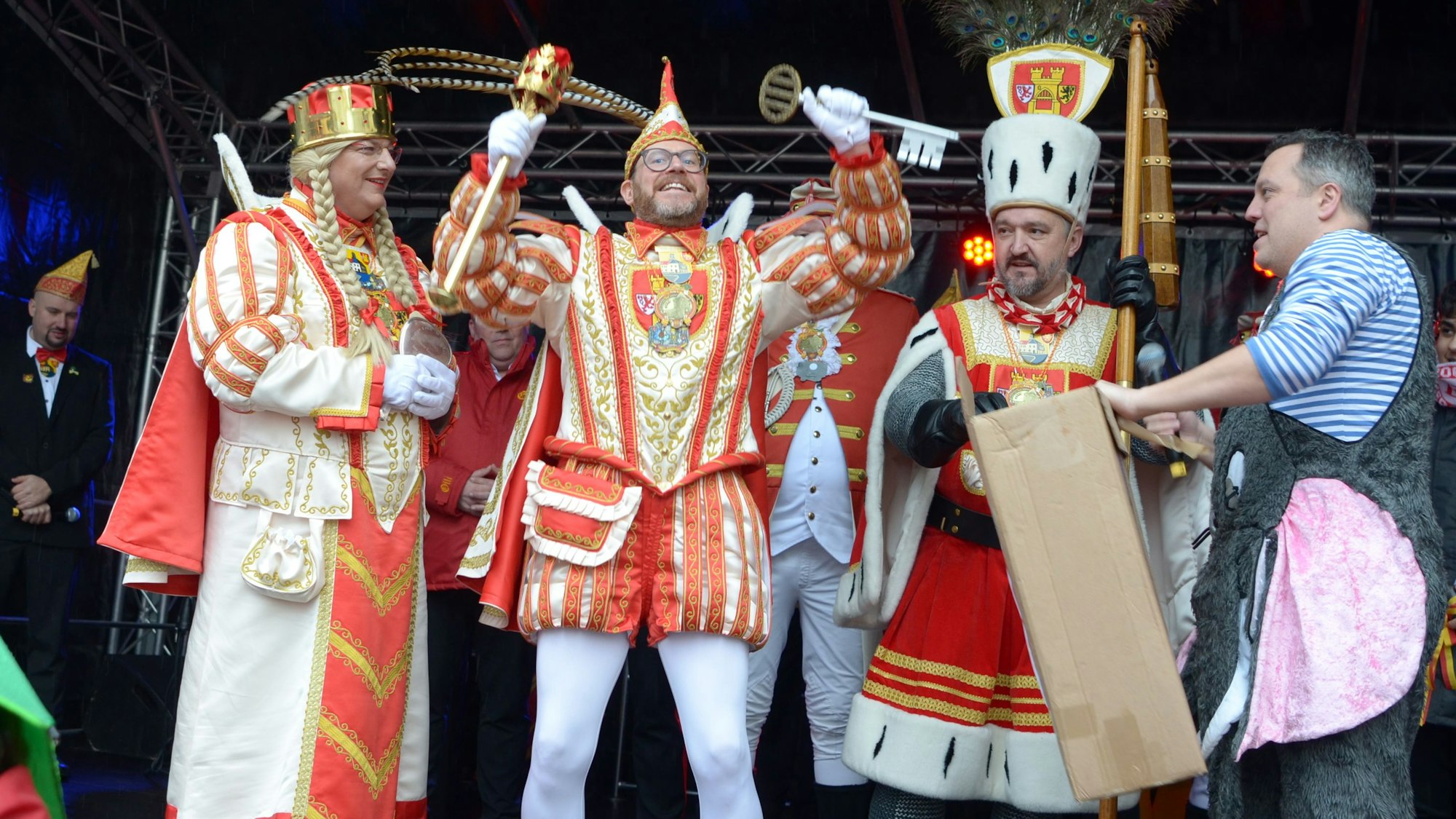 Da ist das Ding! Prinz Tobi I., flankiert von Jungfrau  Martina und Bauer Sascha, präsentiert  den Stadtschlüssel, den er in die Höhe reckt. Am Bildrand steht der geschlagene Bürgermeister Sacha Reichelt.