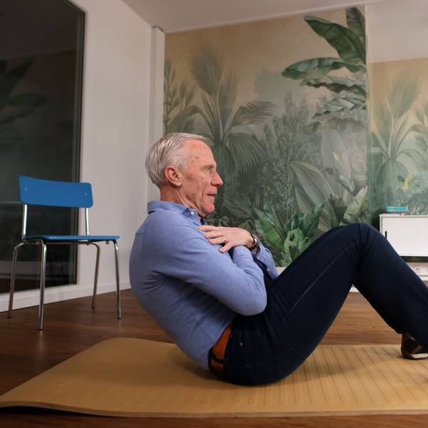 Ingo Froböse zeigt auf der Fitnessmatte eine Übung für die Bauchmuskulatur.
