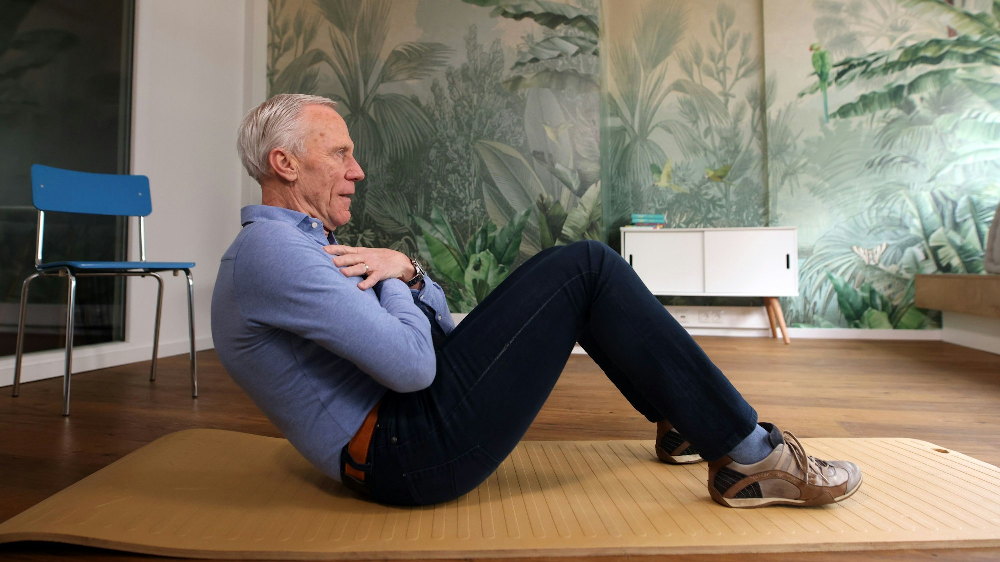 Ingo Froböse zeigt auf der Fitnessmatte eine Übung für die Bauchmuskulatur.