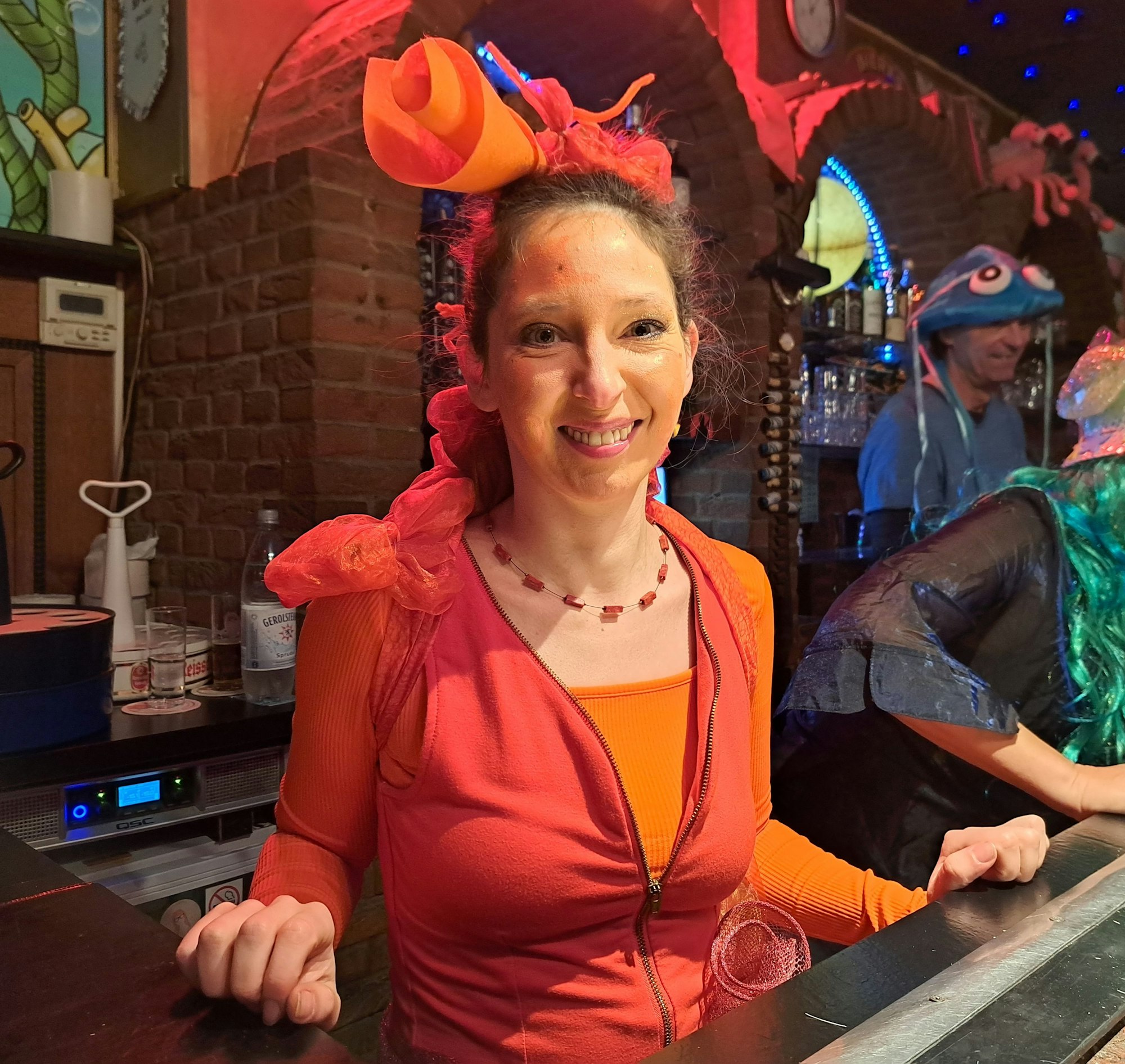 Eine als Seepferdchen verkleidete Frau steht hinter einer Theke.