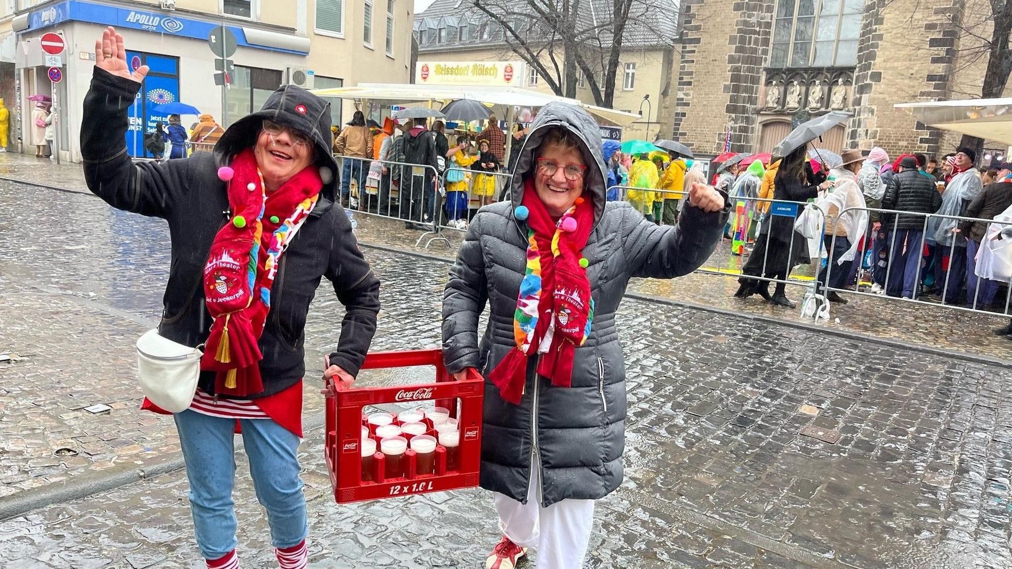 Zwei Frauen tragen Biergläser in einer Cola-Kiste.