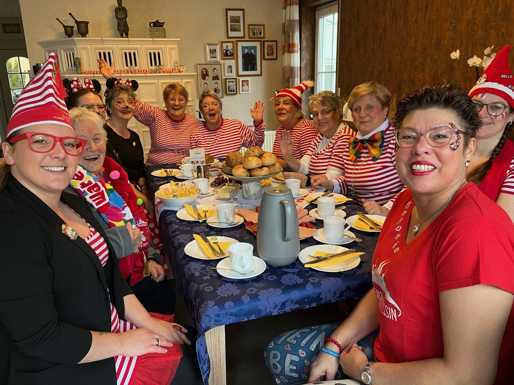 Kostümierte Frauen sitzen am gedeckten Frühstückstisch.