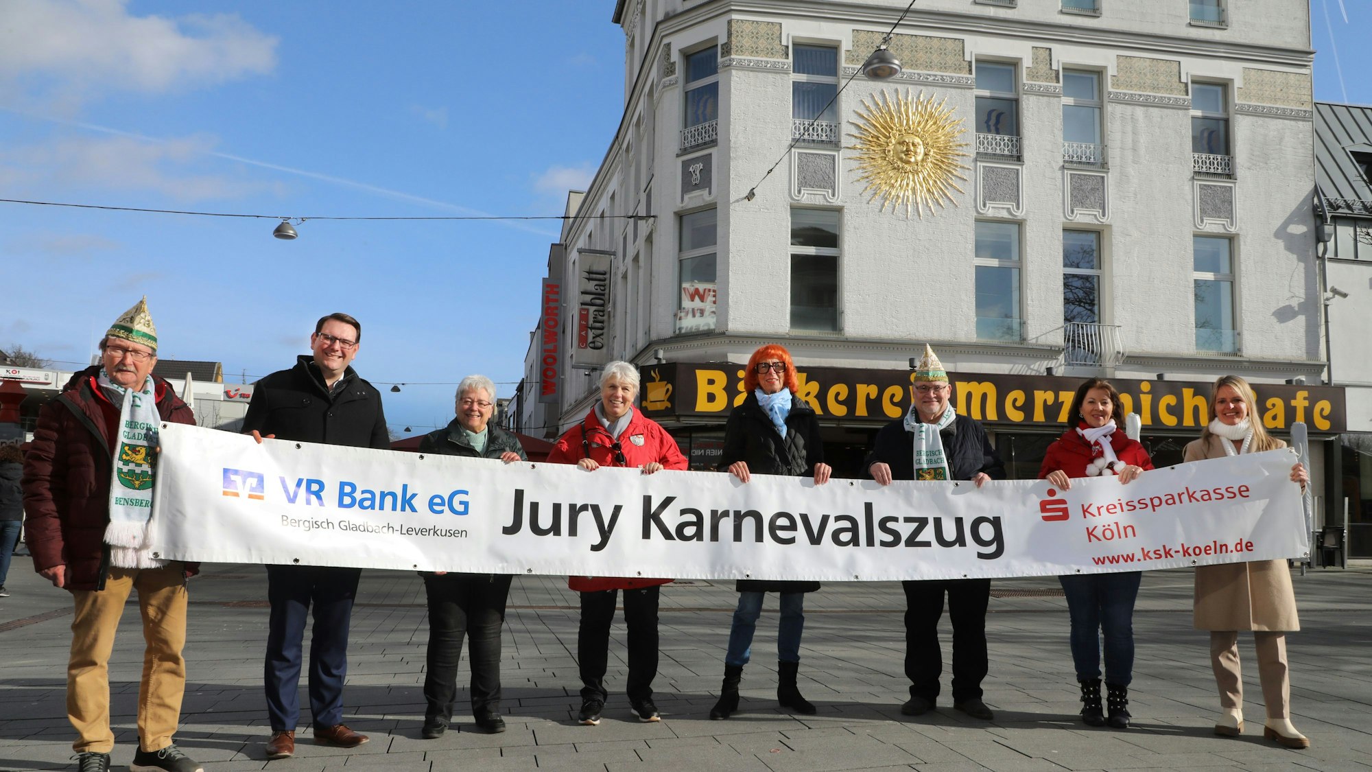 Acht Männer und Frauen halten ein Plakat mit der Aufschrift „Jury Karnevalszug“.