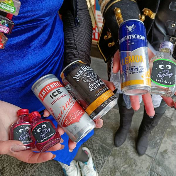 Zwei junge Menschen halten verschiedene alkoholische Getränke in den Händen.