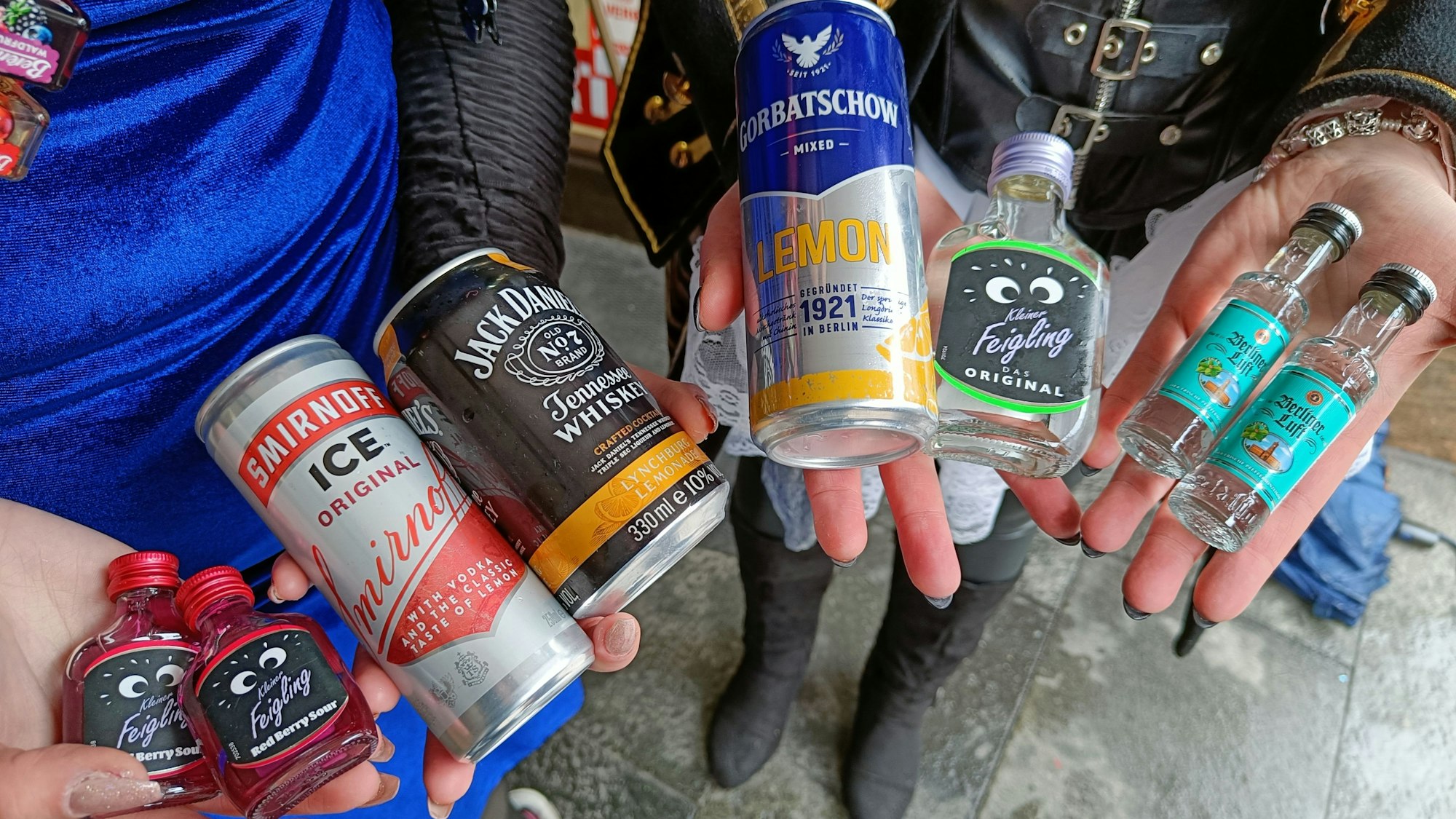 Zwei junge Menschen halten verschiedene alkoholische Getränke in den Händen.