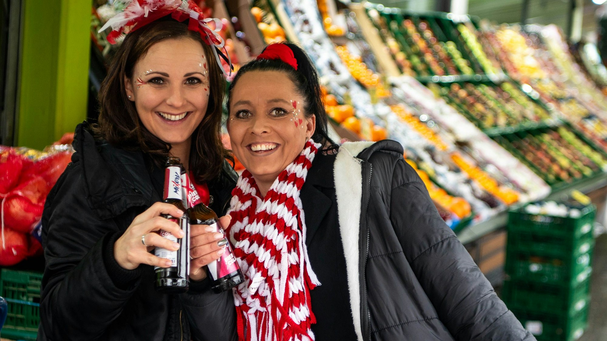 Kölsch im Trockenen unter der Markise trinken Sabrina Steffens (l.) und Nicole Langer. Im Hintergrund erkennt man Obststände.