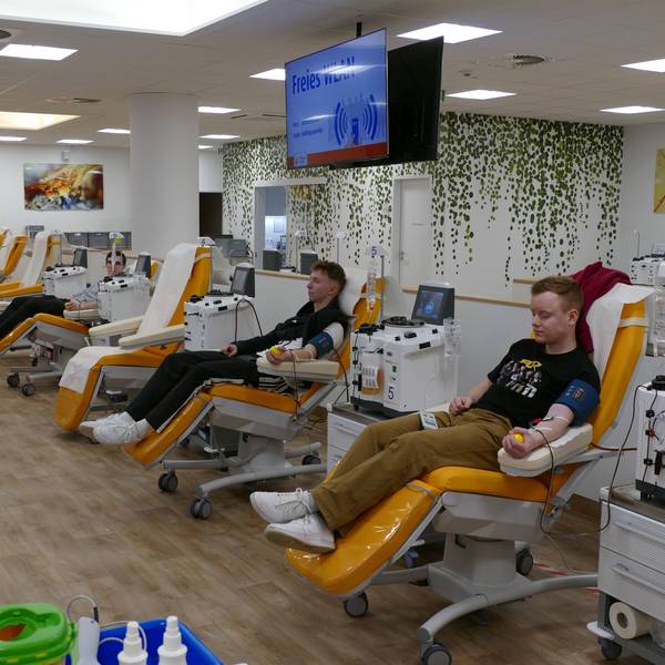 Blick in einen Raum, in dem viele Menschen Blut spenden.