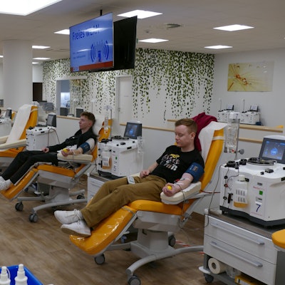 Blick in einen Raum, in dem viele Menschen Blut spenden.