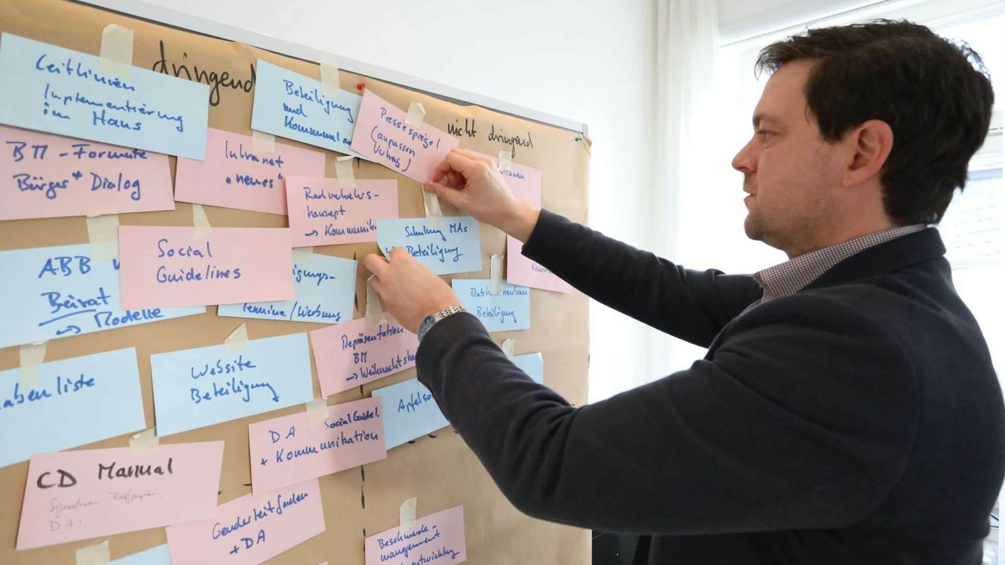 Ein Mann heftet Notizen an eine Pinwand.