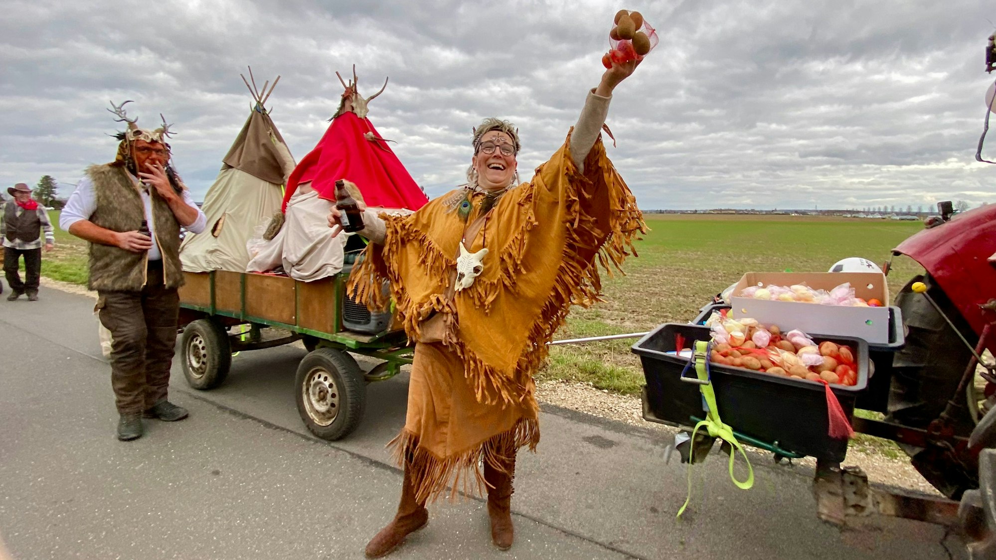 Eine kostümierte Frau hält Kartoffeln hoch.