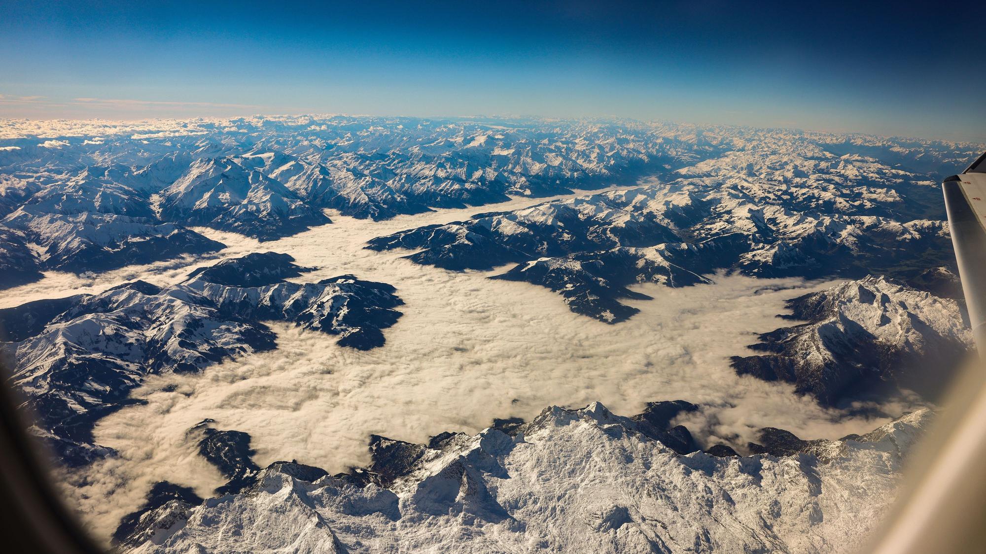 Blick auf verschneite Berggipfel aus einem Flugzeug heraus. (Symbolbild)