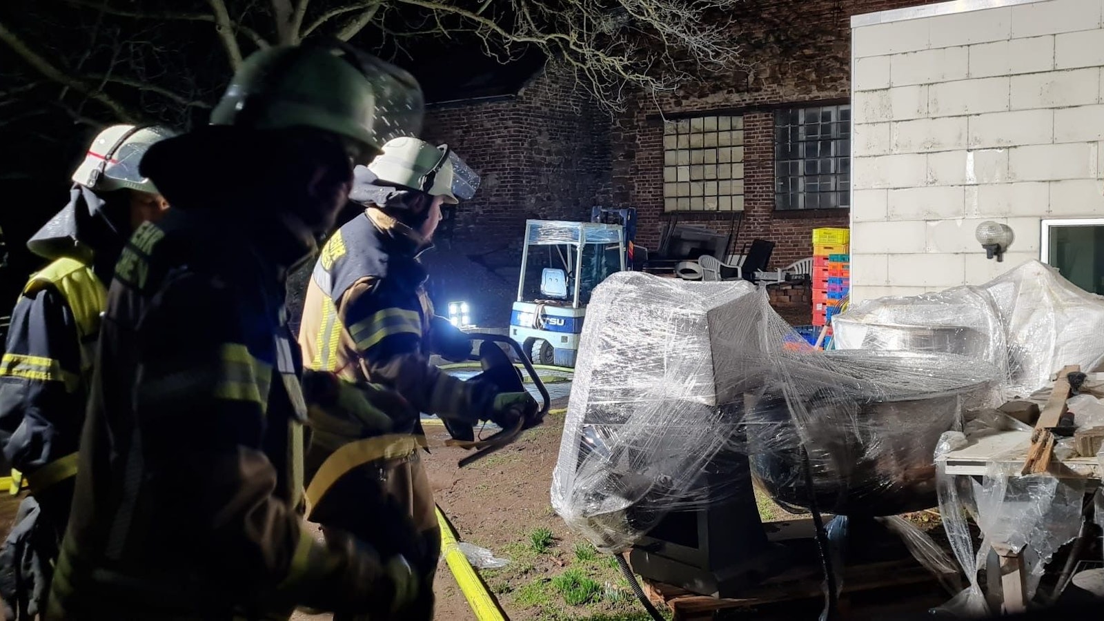 Das Bild zeigt drei Feuerwehreleute in einem Hinterhof während des Einsatzes im Bereich einer Bäckerei.