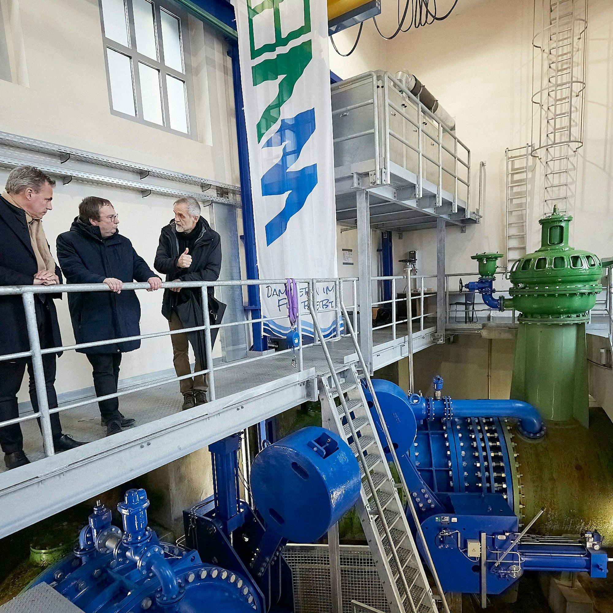 Mark Habers und Oliver Krischer (von links) stehen mit einem Mann in der Rurtalsperre.